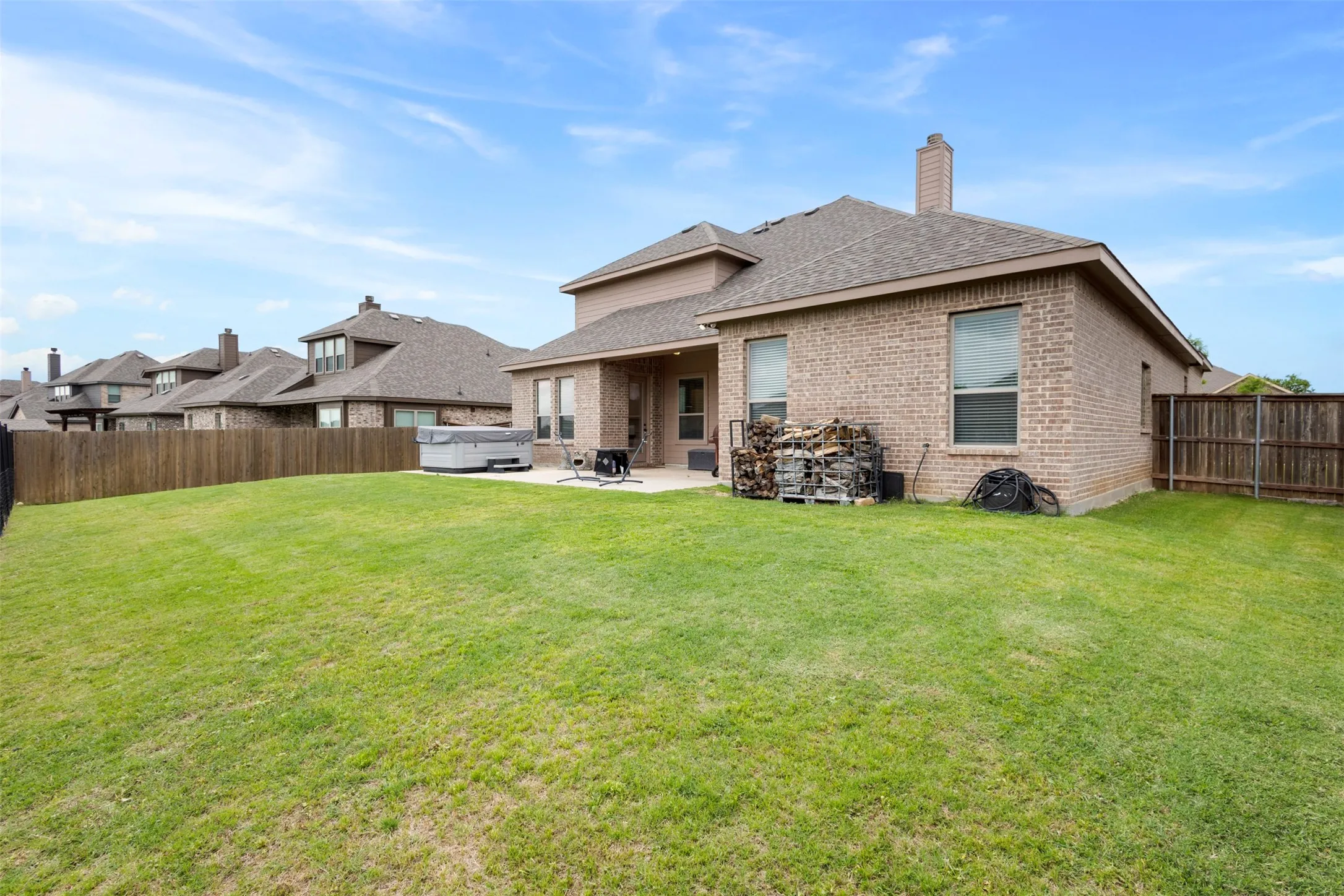 Expansive backyard featuring a large grass lawn, privacy fencing, and a concrete patio