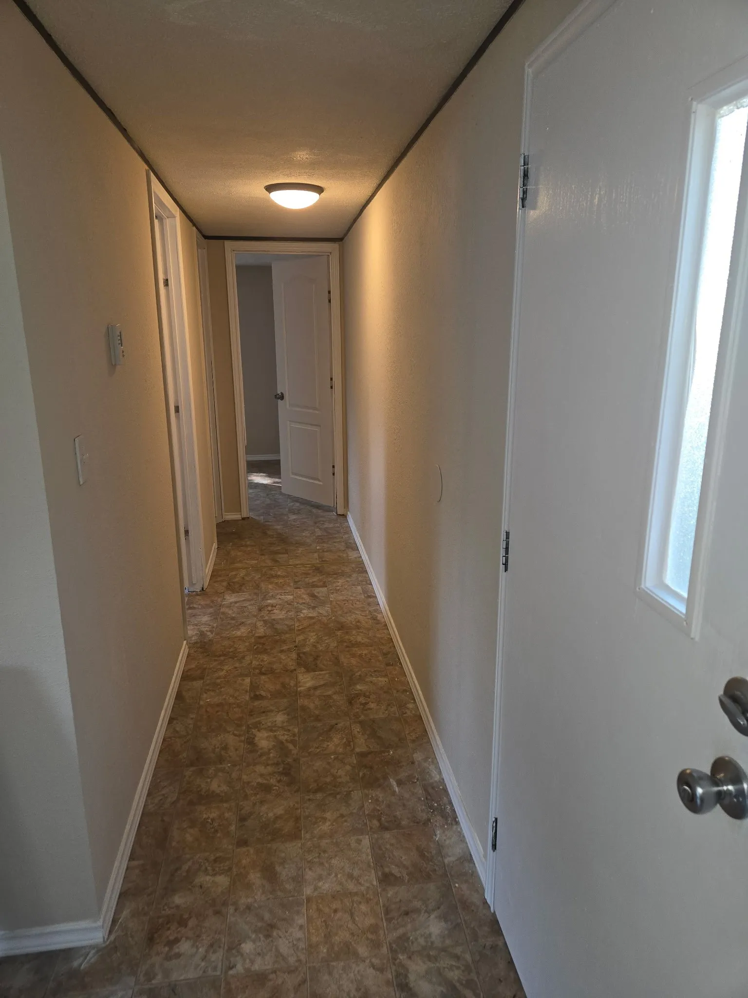 Hallway featuring light neutral wall paint, white trim, and patterned resilient flooring