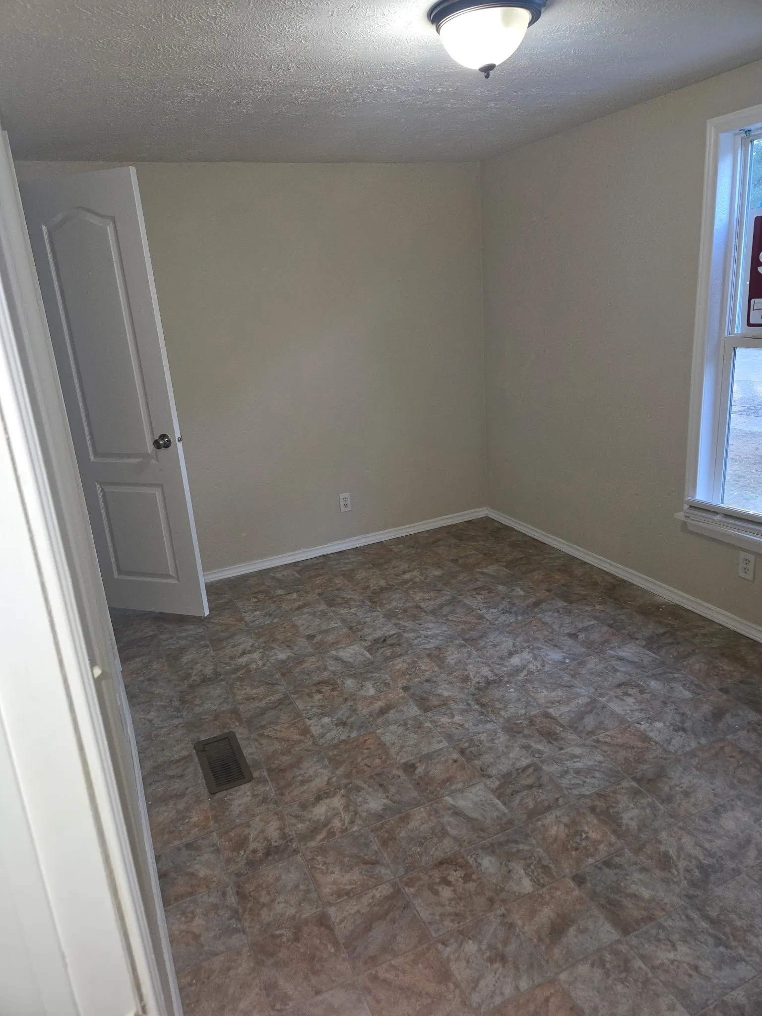 Room featuring neutral-toned walls, tile-patterned flooring, white trim, a semi-flush mount ceiling light, and a window