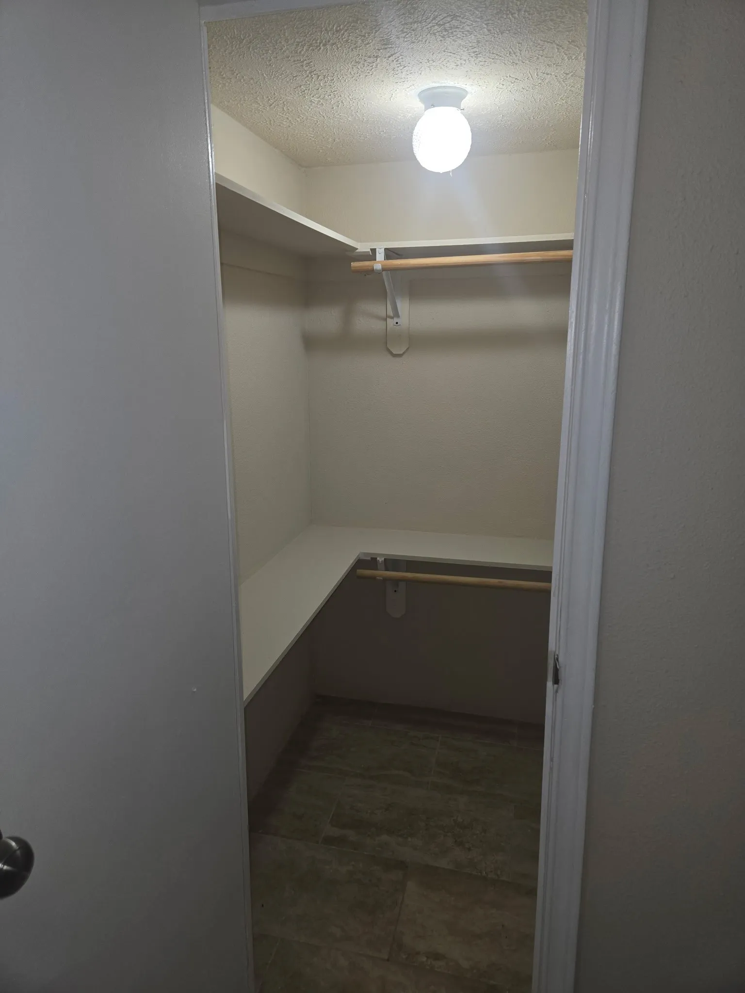 Walk-in closet featuring built-in shelving, hanging rods, and a tiled floor