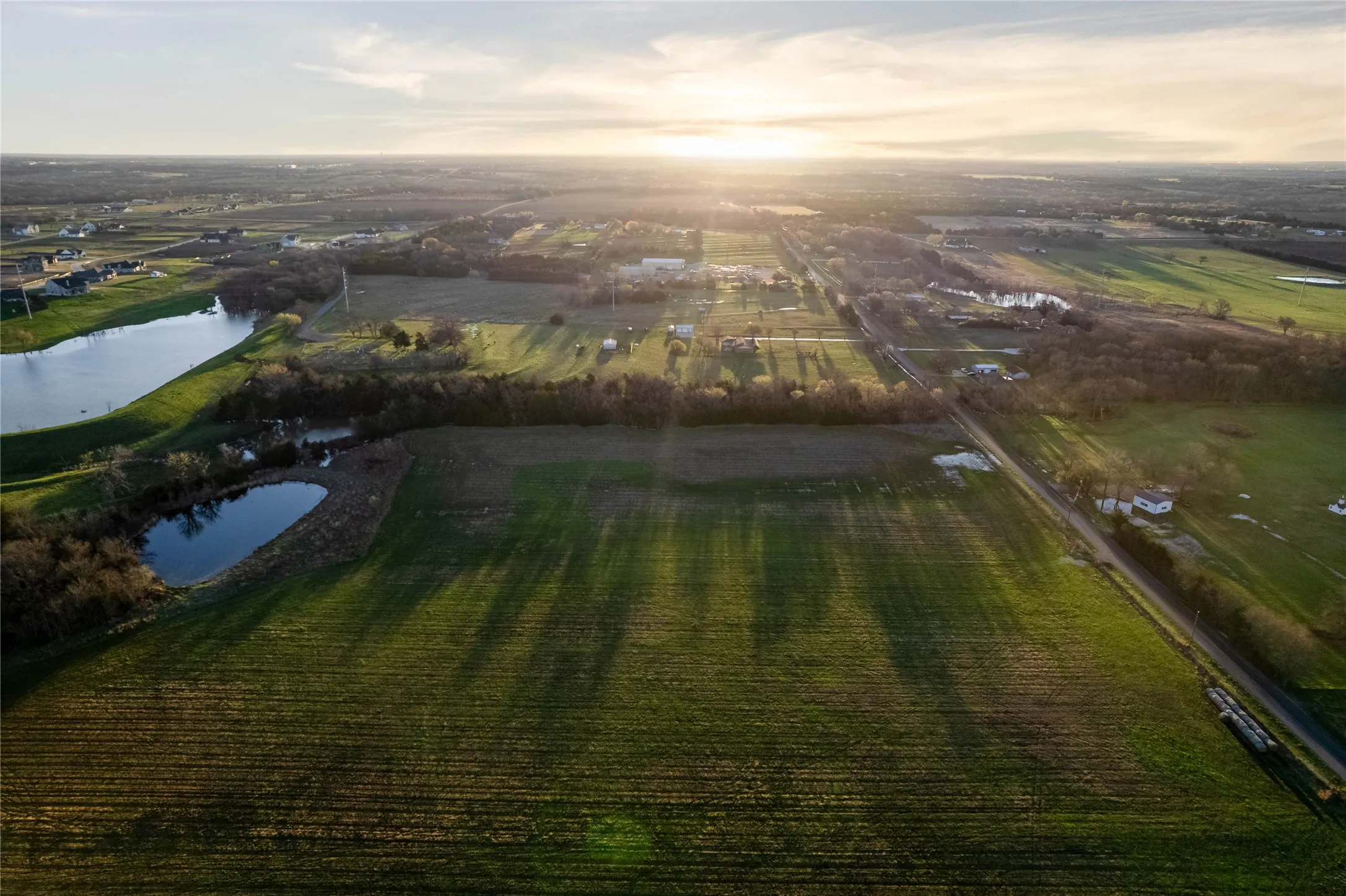 Expansive acreage featuring cultivated fields, a substantial pond, and a distinct tree line