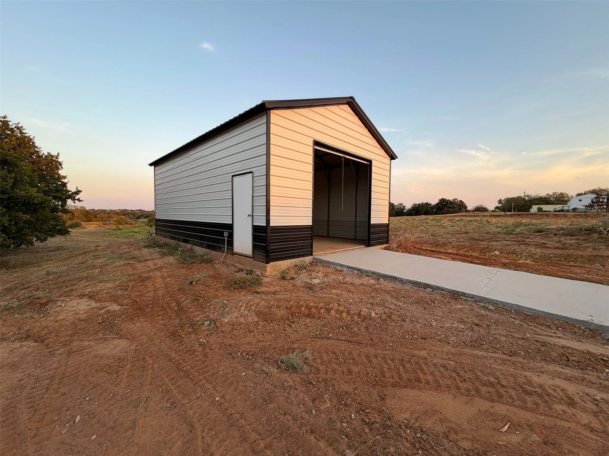 Detached structure featuring metal siding, a roll-up door, a pedestrian door, and a concrete approach