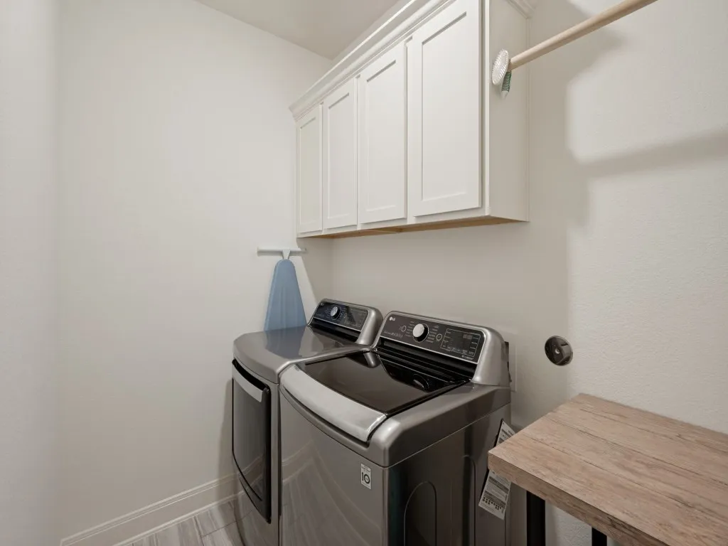 The spacious laundry room has built-in cabinets and a rod for hanging up clothes right out of the dryer!