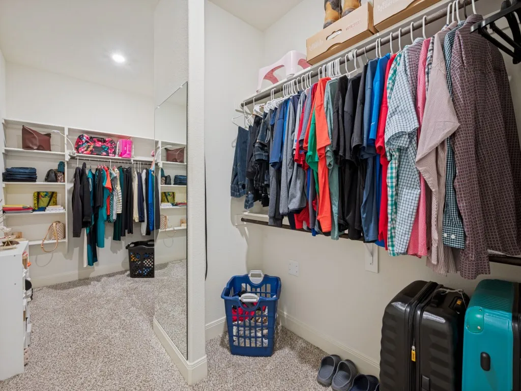 This absolutely huge walk-in primary closet features built-in shelving, abundant hanging space, and a full-length mirror, offering exceptional organization and storage.