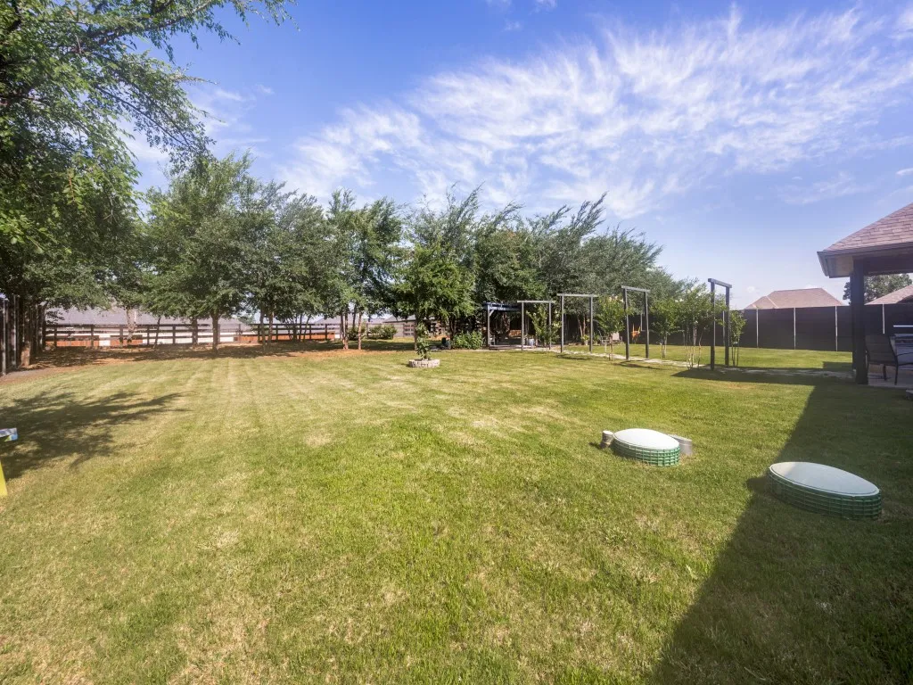 Plenty of room for kids to play and dogs to run. Private lot with view of the beautiful Texas sky, private fence along the sides, tree line along the back fence, charming walkway to the oversized backyard pergola with hanging bench and egg chair.