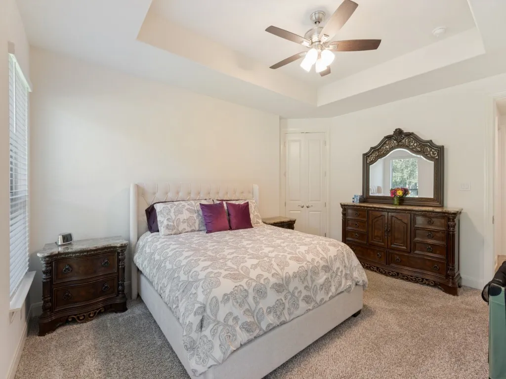 Spacious primary bedroom featuring a tray ceiling, large windows, and ensuite bath