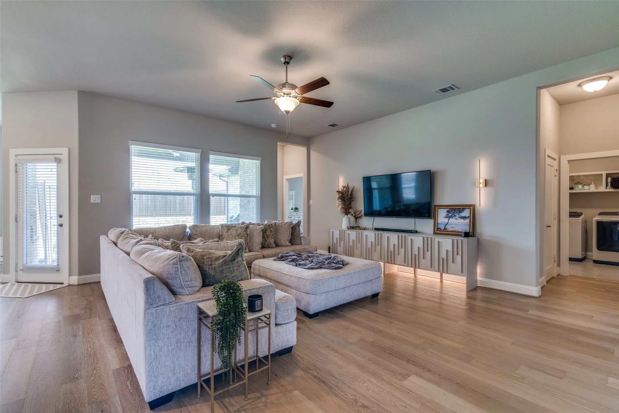 Spacious living area featuring wood-finish flooring, vaulted ceilings, and a ceiling fan with integrated lighting