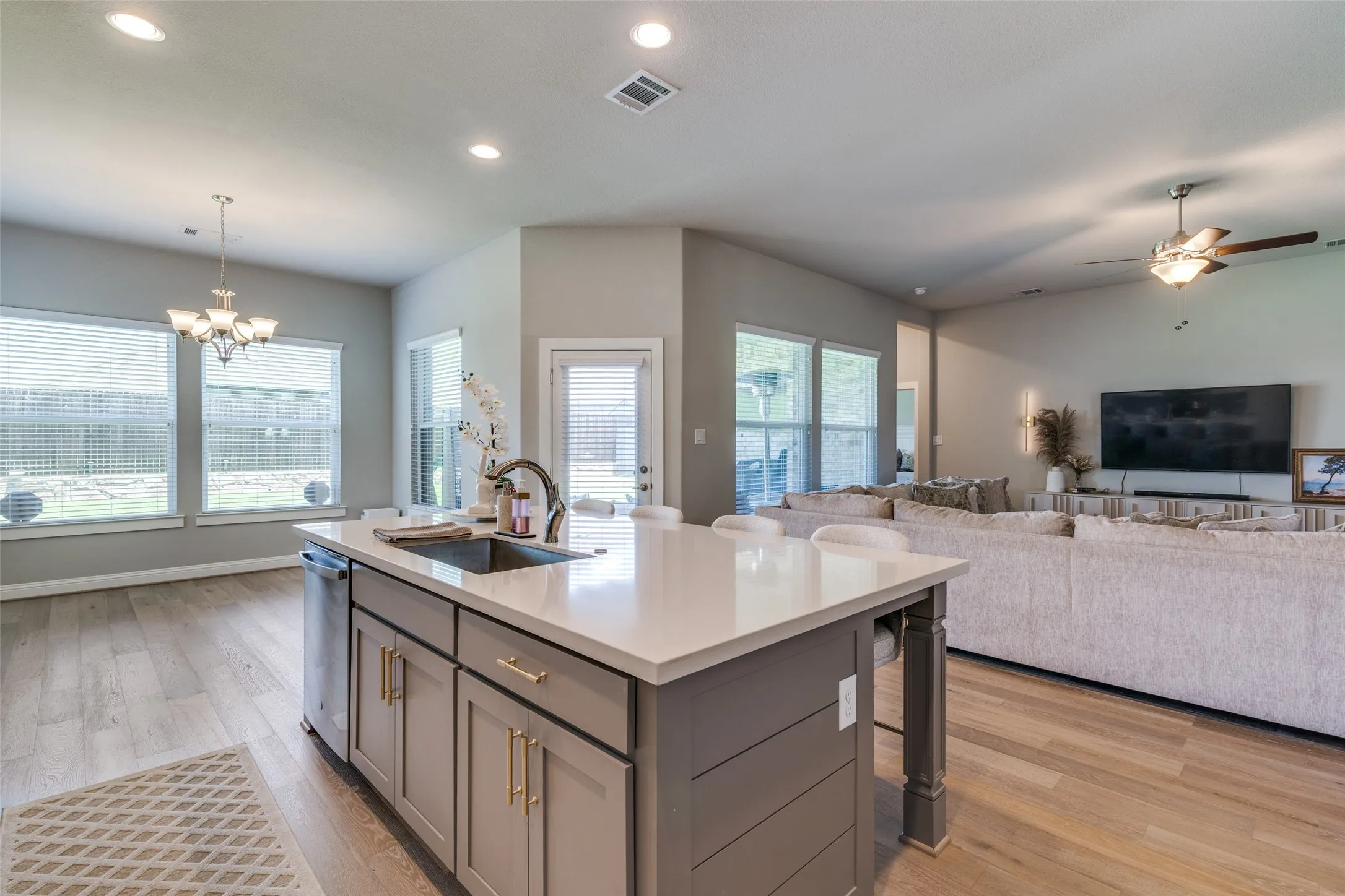 Spacious kitchen island with a built-in sink, stainless steel dishwasher, and light-toned countertop
