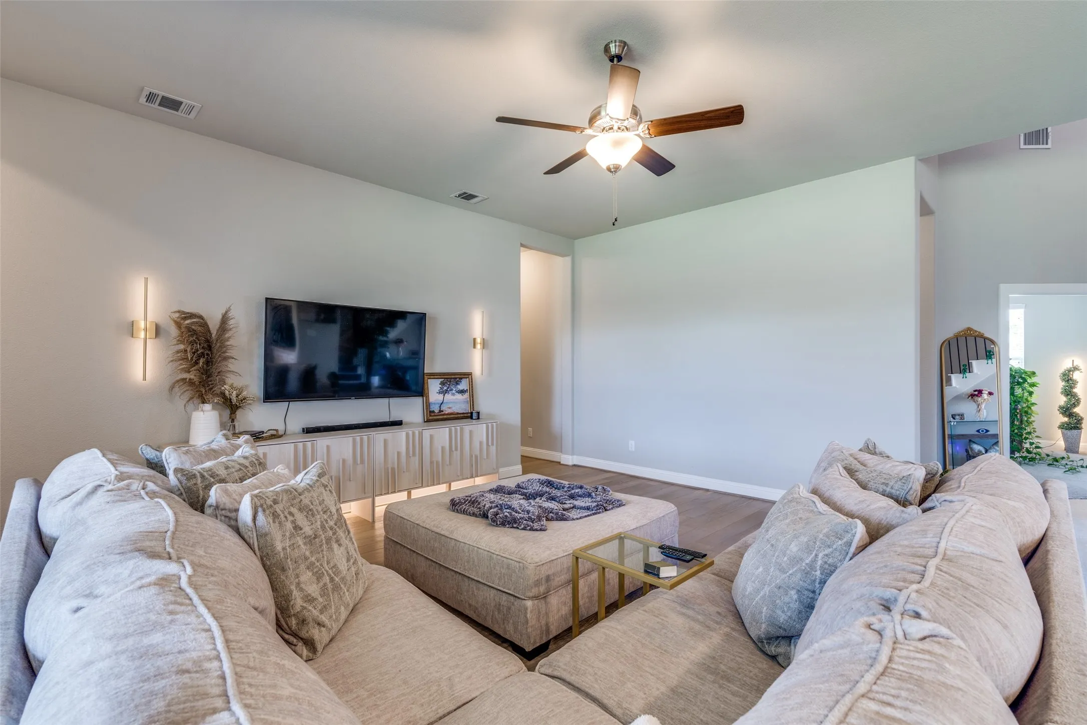 Spacious living area featuring light-toned walls, recessed lighting, and wood-finish flooring