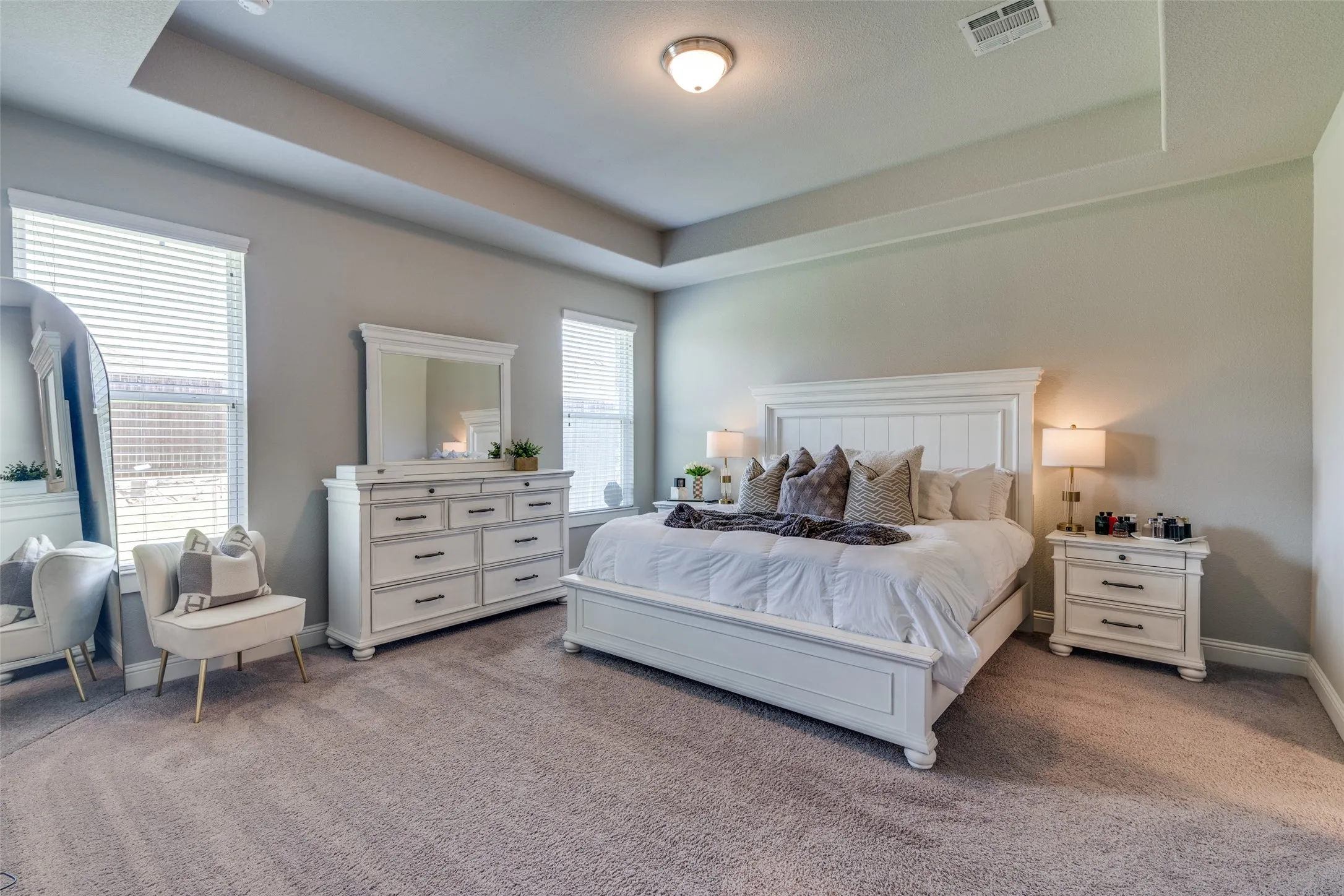 Spacious room featuring a tray ceiling, recessed lighting, carpet flooring, and multiple windows with blinds