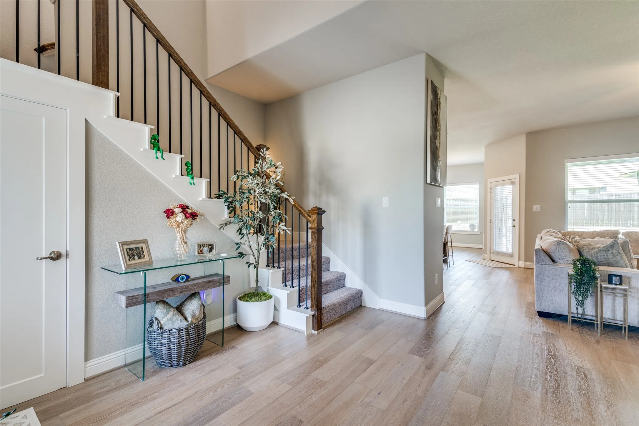 Open-concept main level featuring wood-finish flooring, a contemporary staircase with iron balusters and wood handrail, and light gray wall tones