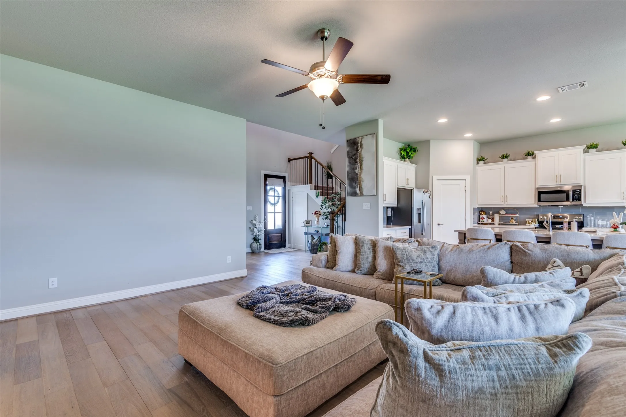 Open-concept living space featuring wood-finish flooring, recessed lighting, and a ceiling fan