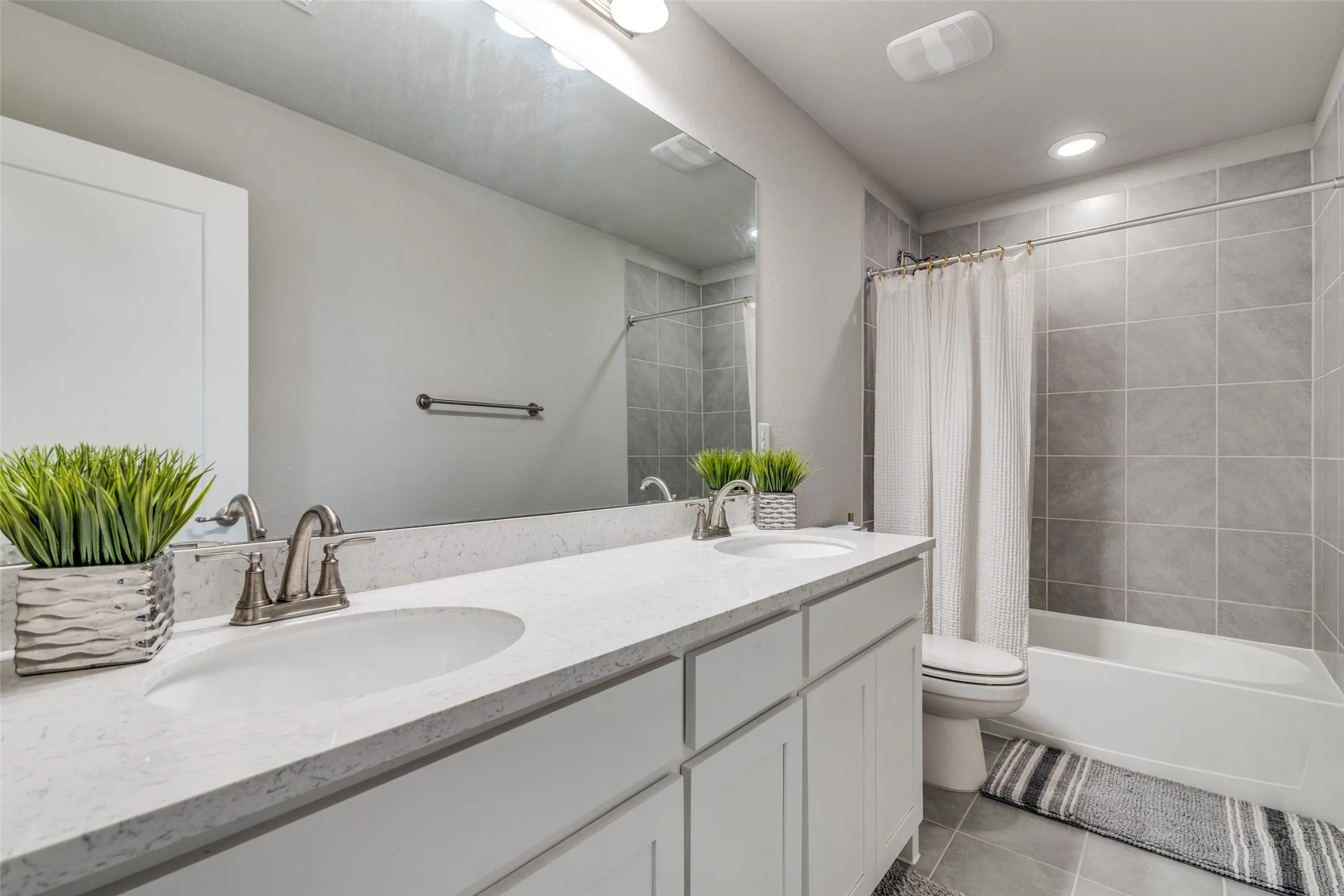 Bathroom featuring a dual-sink vanity with a light-toned countertop, white cabinetry, and brushed nickel fixtures