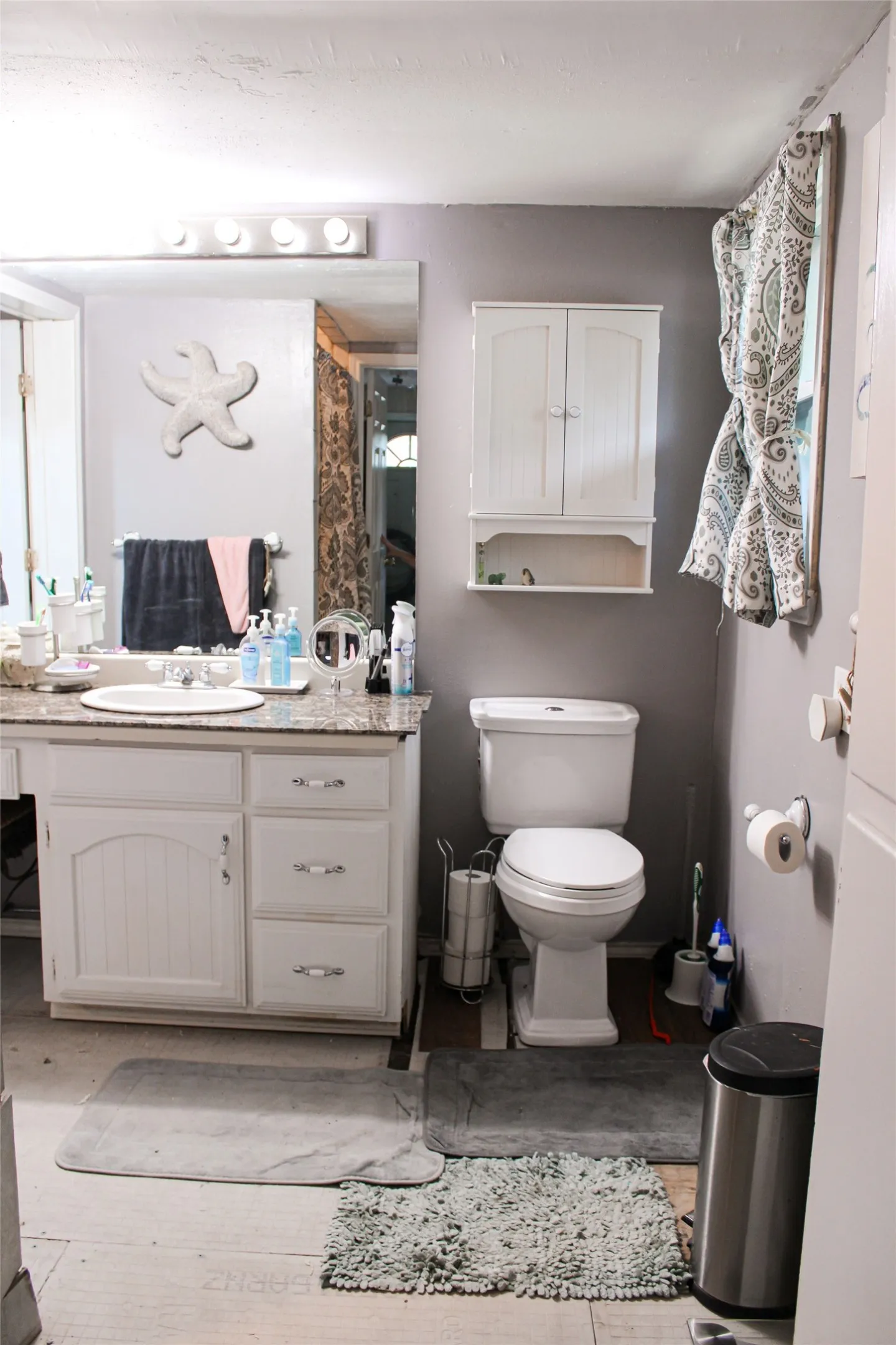 Bathroom featuring a white vanity with beadboard paneling, a granite-look countertop, and an undermount sink