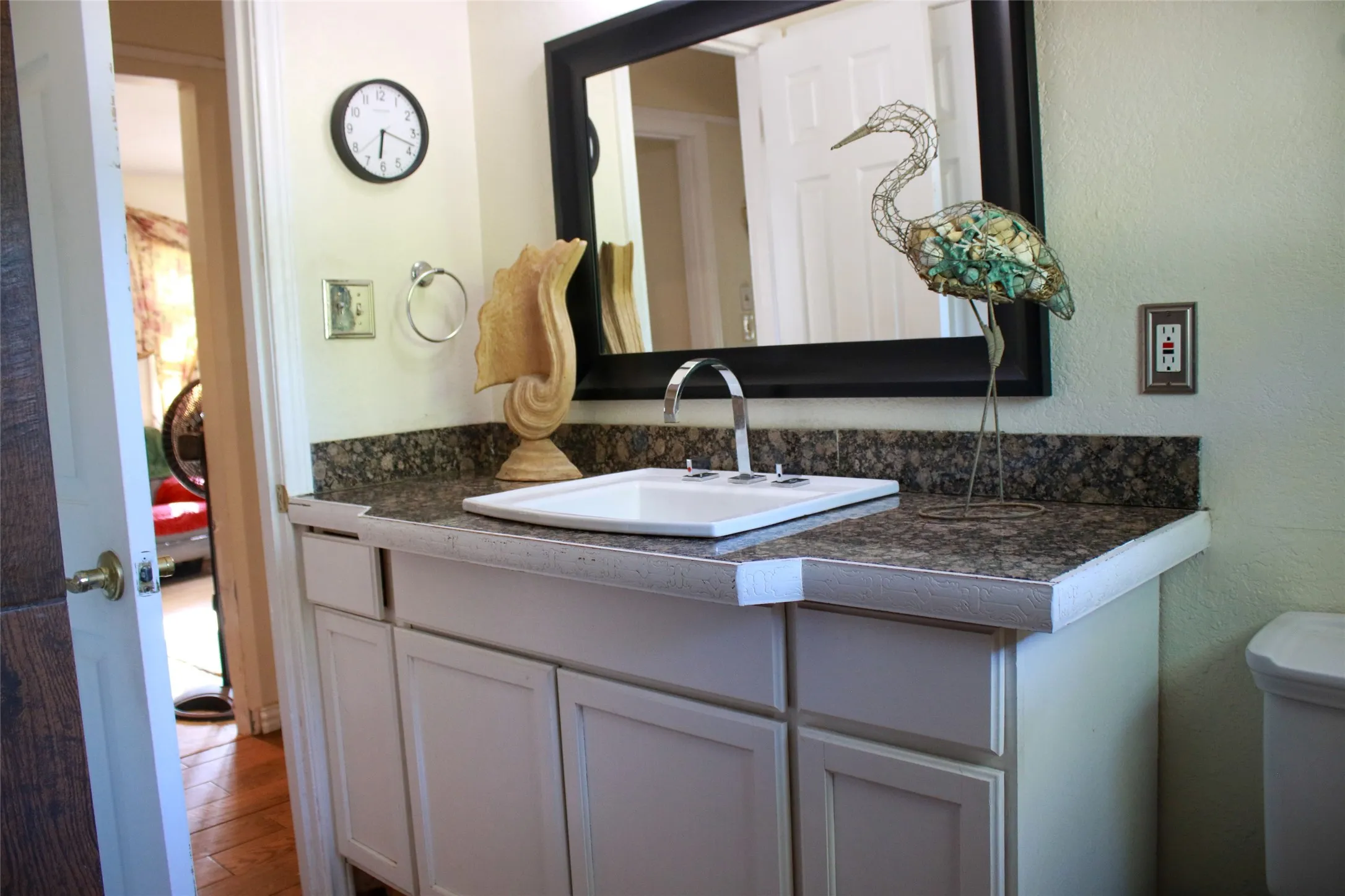 White shaker-style vanity with dark granite-patterned countertop, under-mount sink, and framed mirror