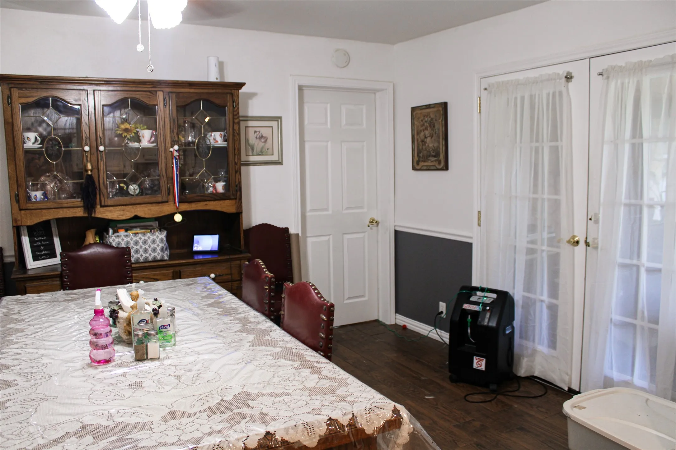 Dining area with wood-finish flooring, two-tone wall paneling, and a ceiling fan with light fixture