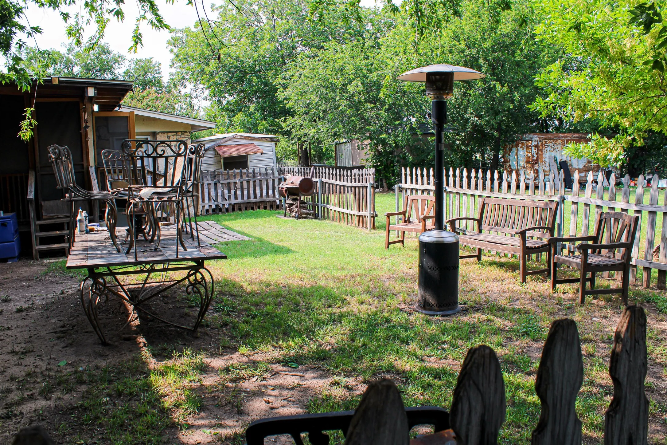 Fenced yard featuring a wooden deck with railing, a storage shed, and mature trees