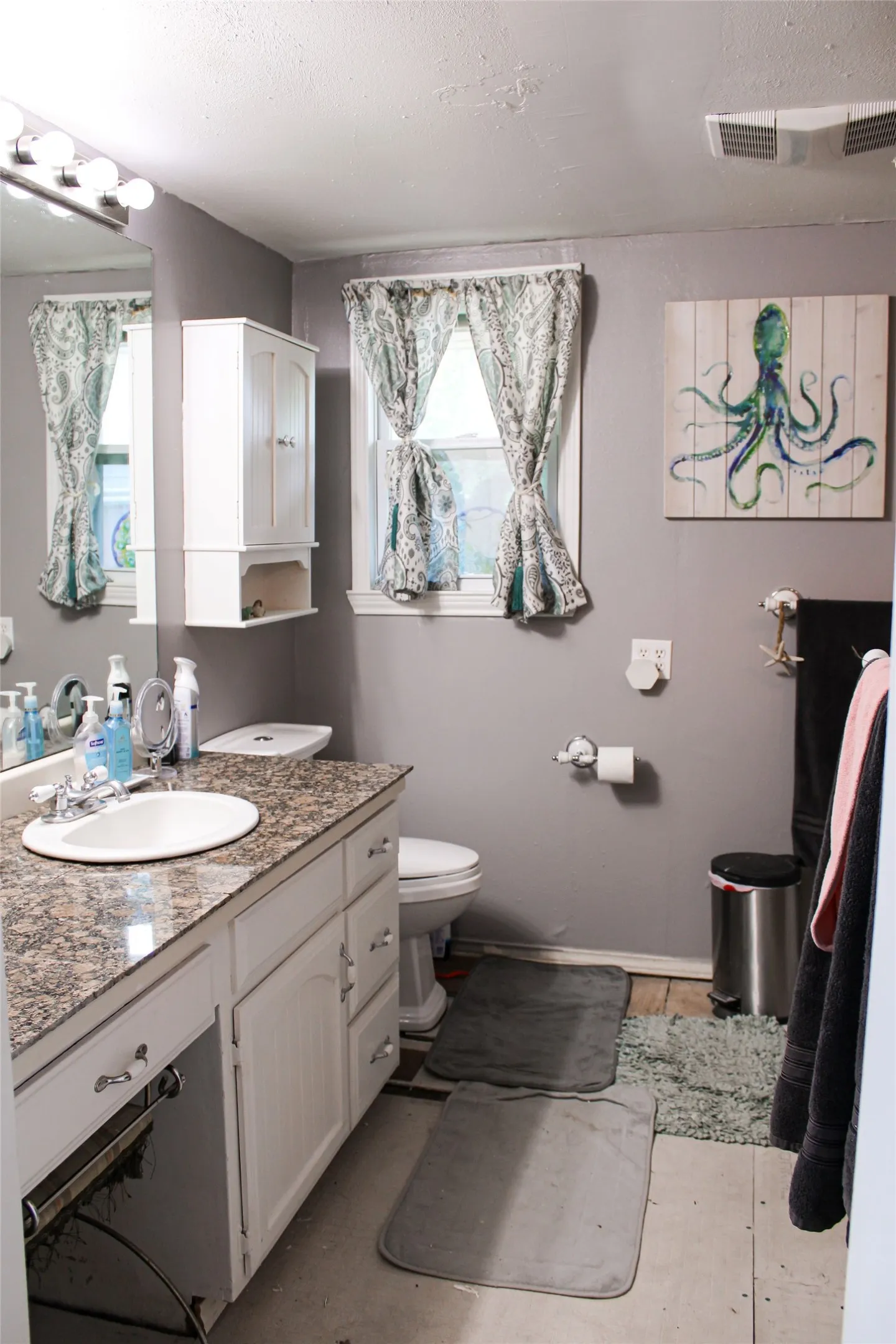 Bathroom featuring a white vanity with a built-in sink, stone-finish countertop, and white cabinetry