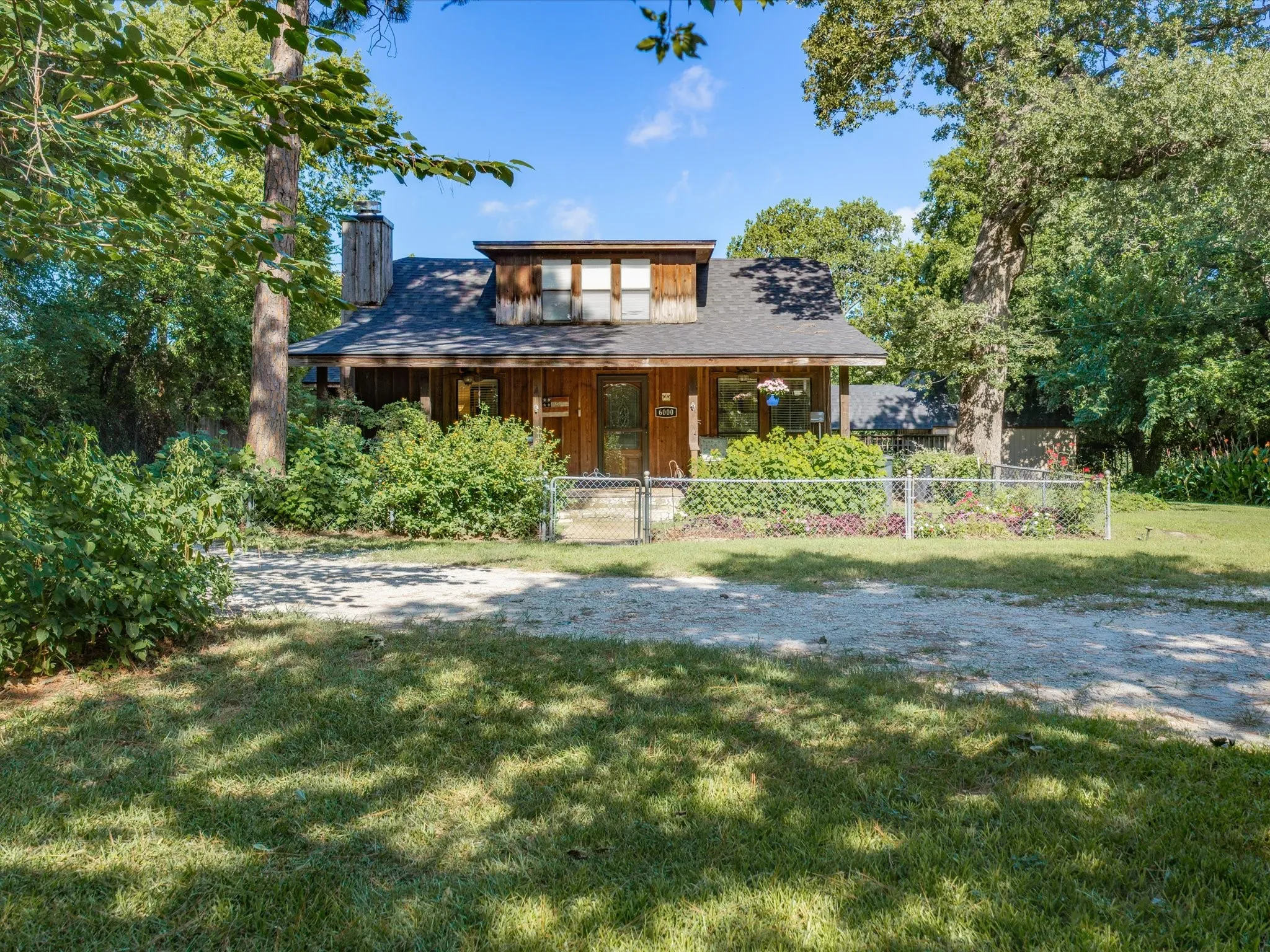 Wood-sided property featuring a dark shingled roof and a prominent chimney structure