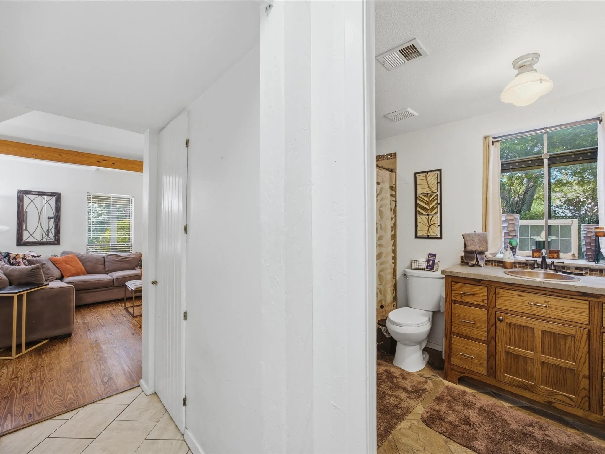 Bathroom featuring a wood-finish vanity with a built-in sink, a window with exterior views, and a traditional ceiling light fixture
