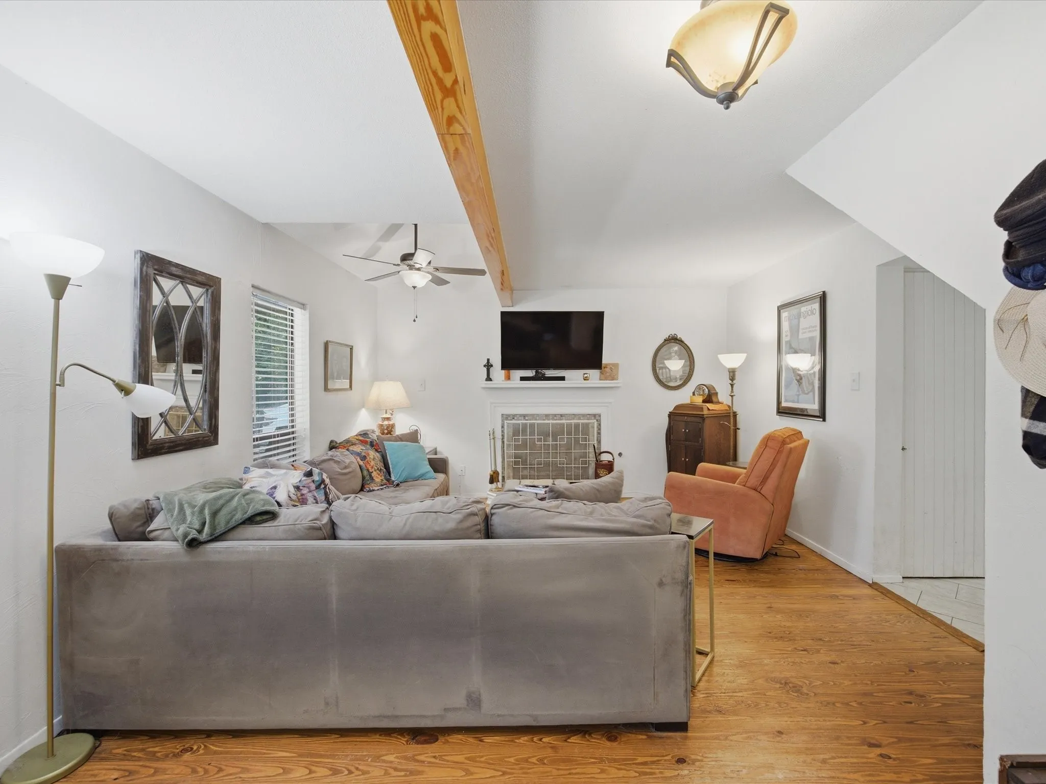 Living area featuring natural wood-finish flooring, white walls, and an exposed wood beam