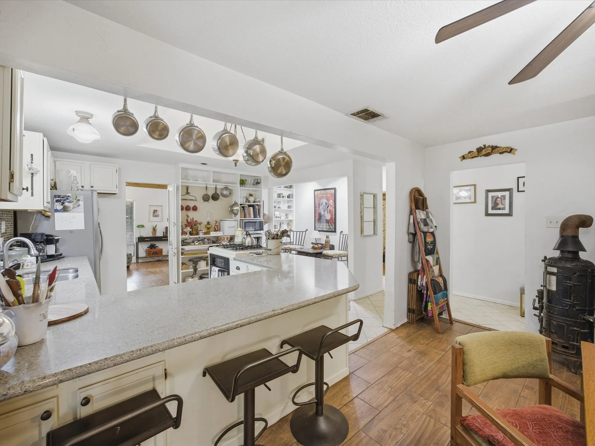 Kitchen featuring a breakfast bar with stone-finish countertop, white cabinetry, and wood-finish flooring
