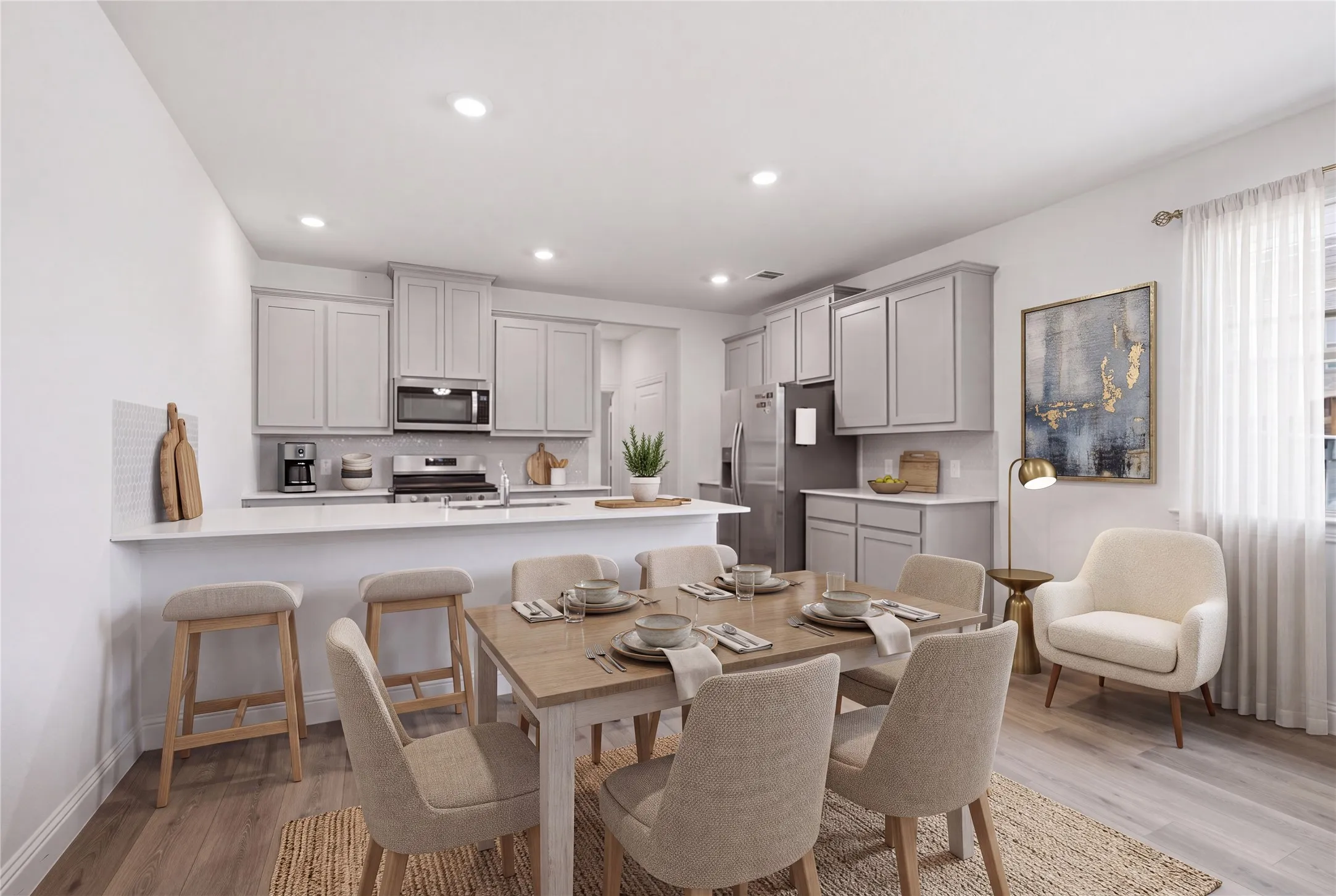 Open-concept living space with wood-finish flooring, recessed lighting, and a kitchen featuring light gray cabinetry and stainless steel appliances