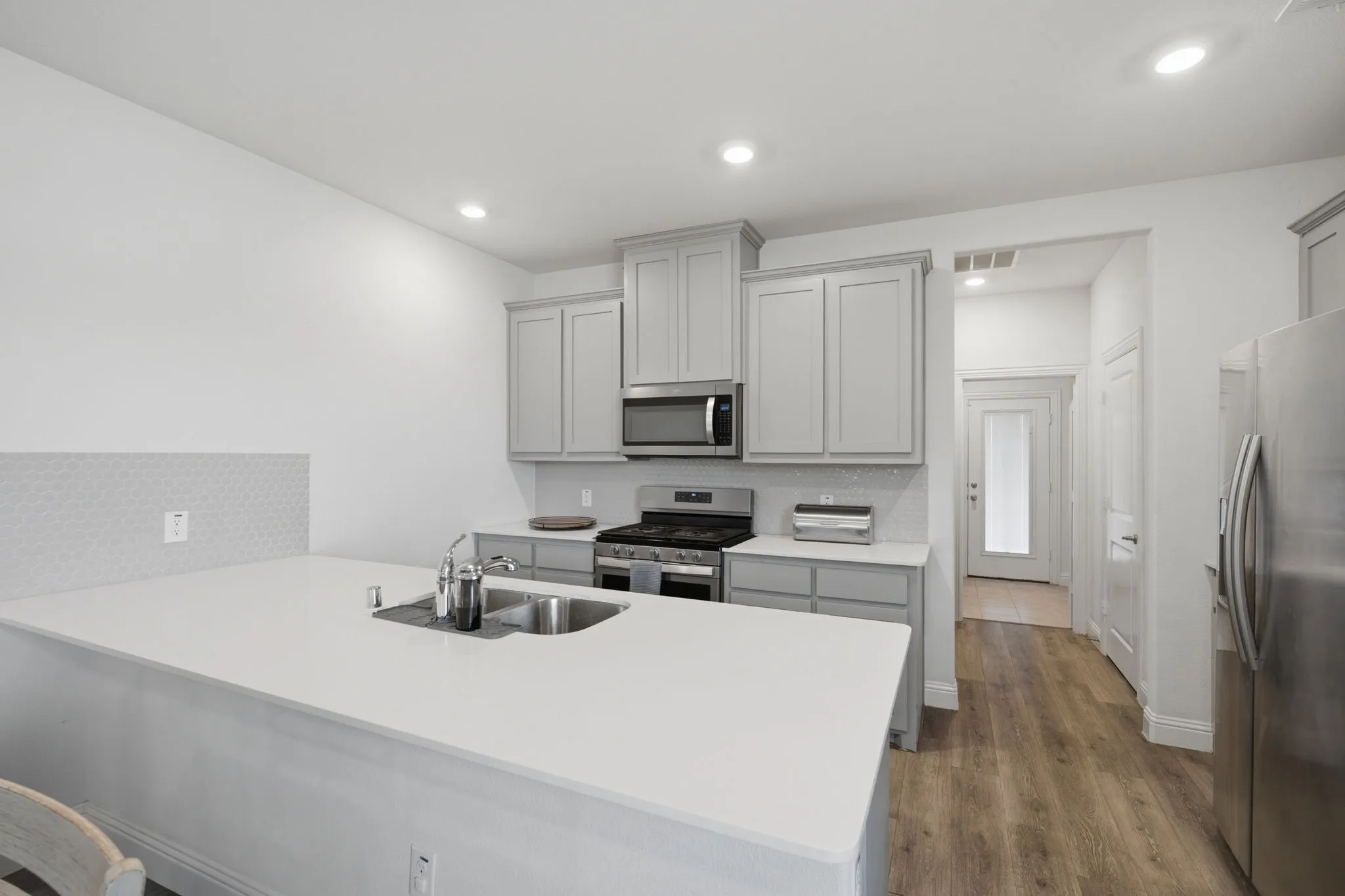 Contemporary kitchen featuring light gray cabinetry and stainless steel appliances