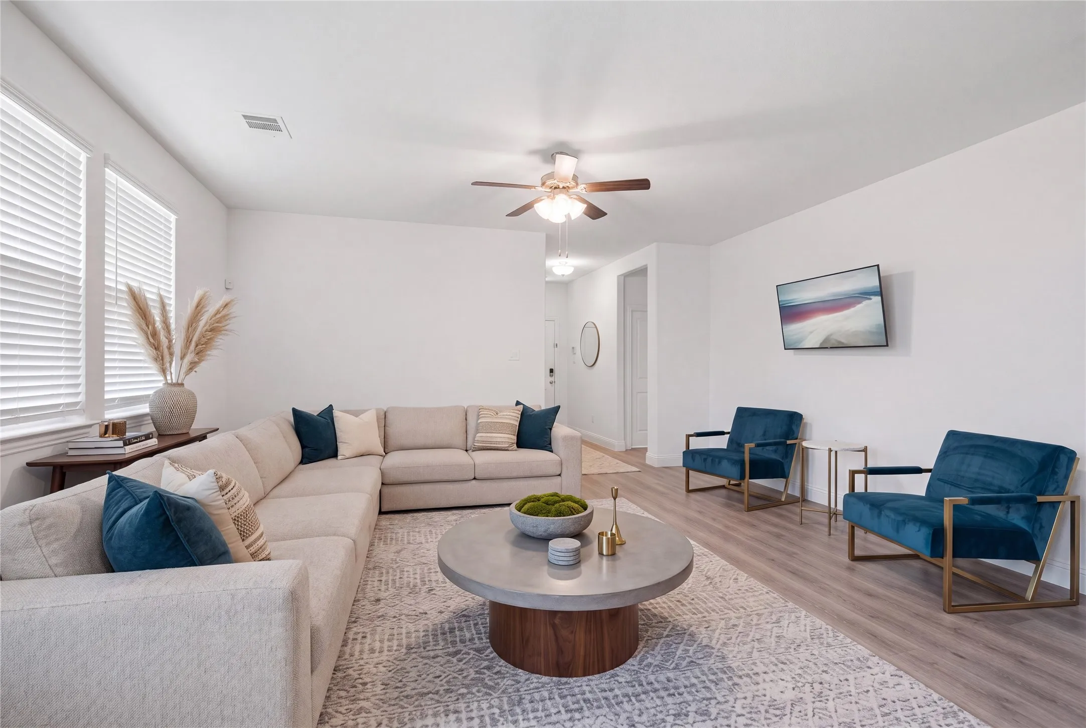 Spacious living area featuring light-tone wood-finish flooring and crisp white walls