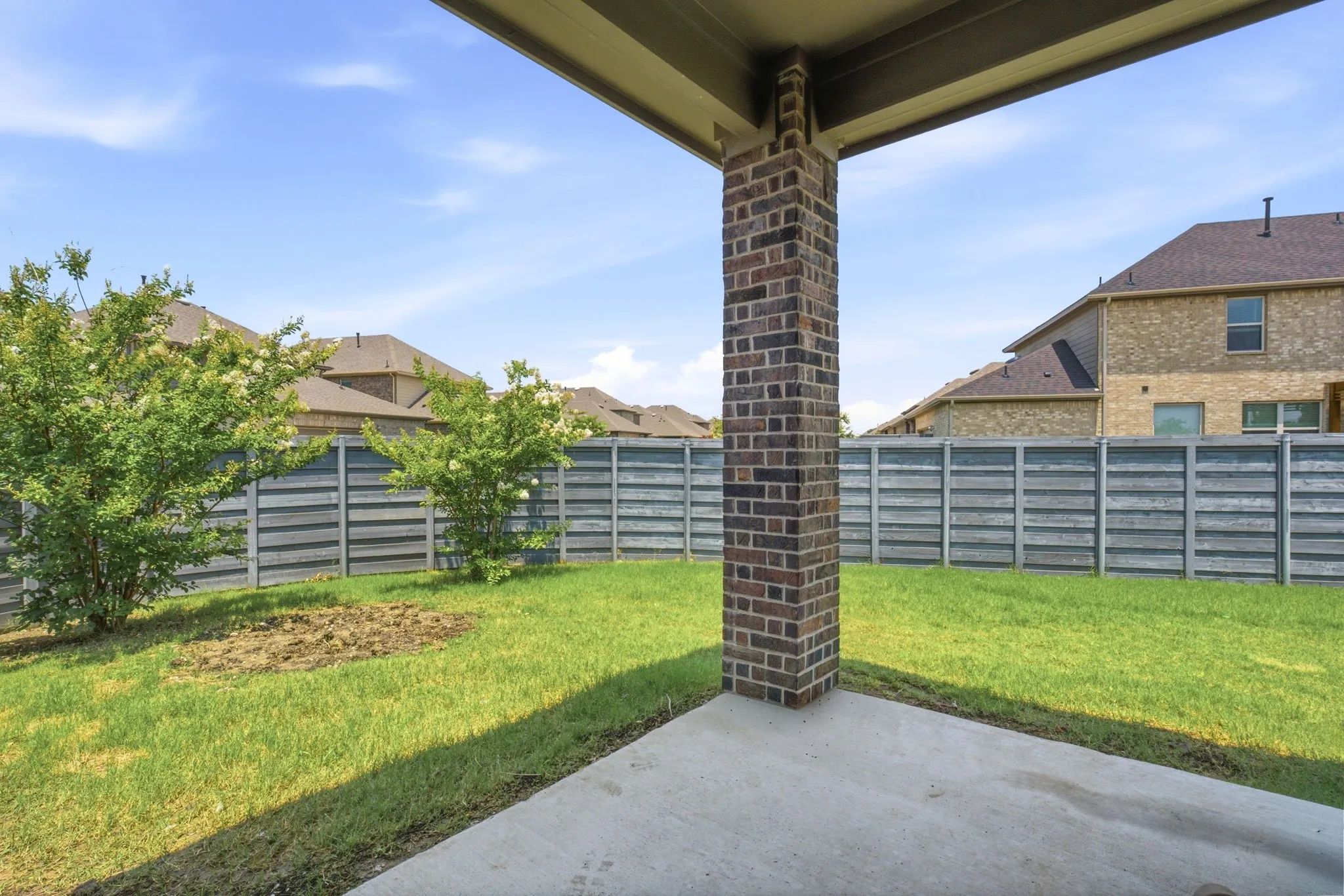 Expansive green space featuring a large open field, mature trees, paved walking paths, and a community building with a circular drop-off area