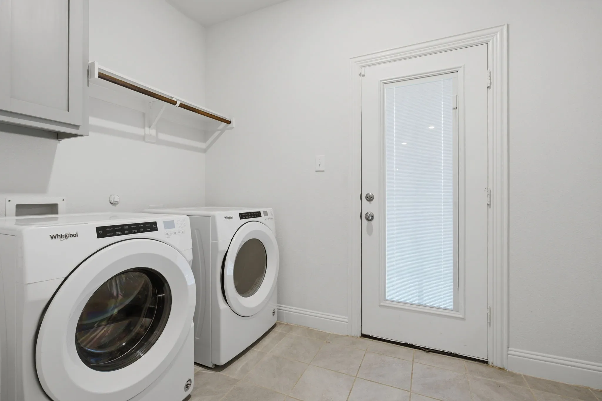 Dedicated laundry space featuring neutral wall paint and tile flooring