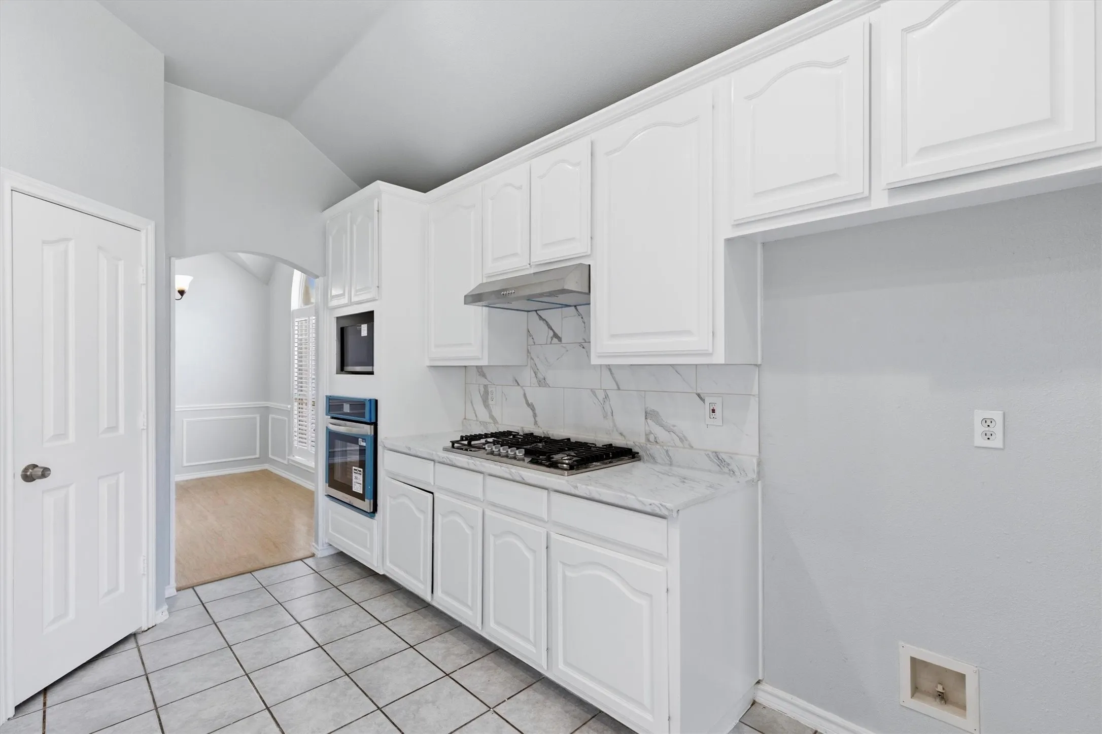 Kitchen featuring white cabinetry, built-in oven, gas cooktop, and patterned backsplash
