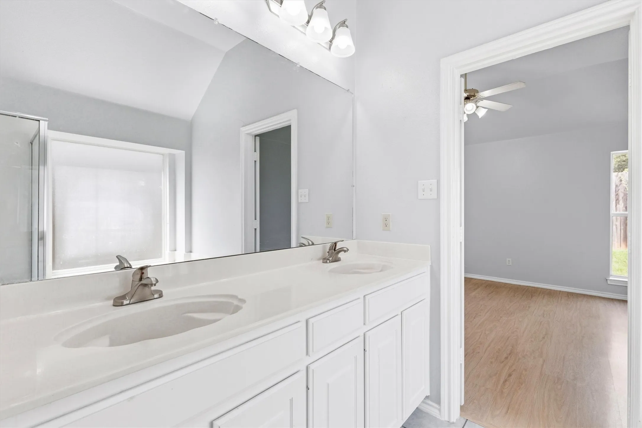 Double vanity with integrated sinks, brushed nickel faucets, and under-cabinet storage