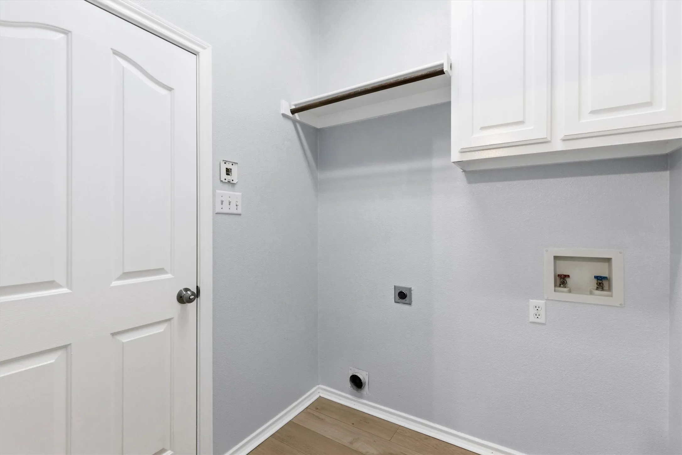 Utility space featuring light wood-finish flooring, white baseboards, and light gray walls