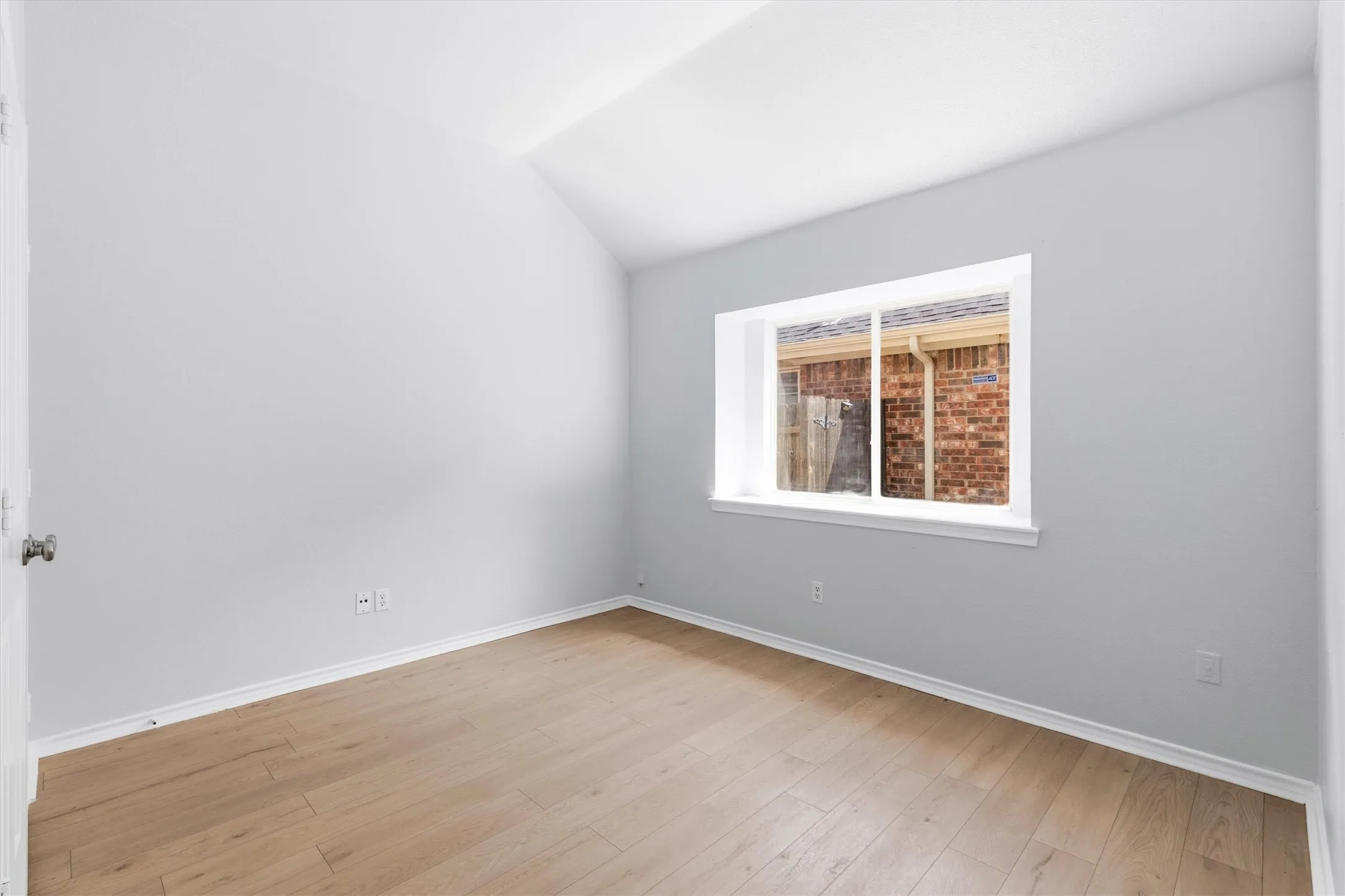 Bright room featuring wood-finish flooring, white baseboards, and a single window with white trim
