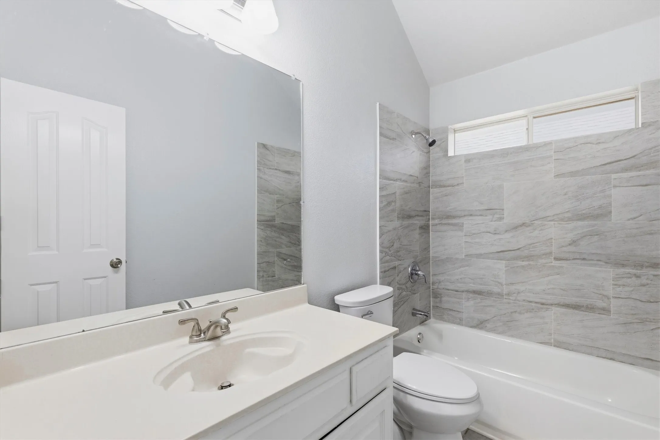 Bathroom featuring a single vanity with an integrated sink, polished chrome faucet, and a large wall-mounted mirror