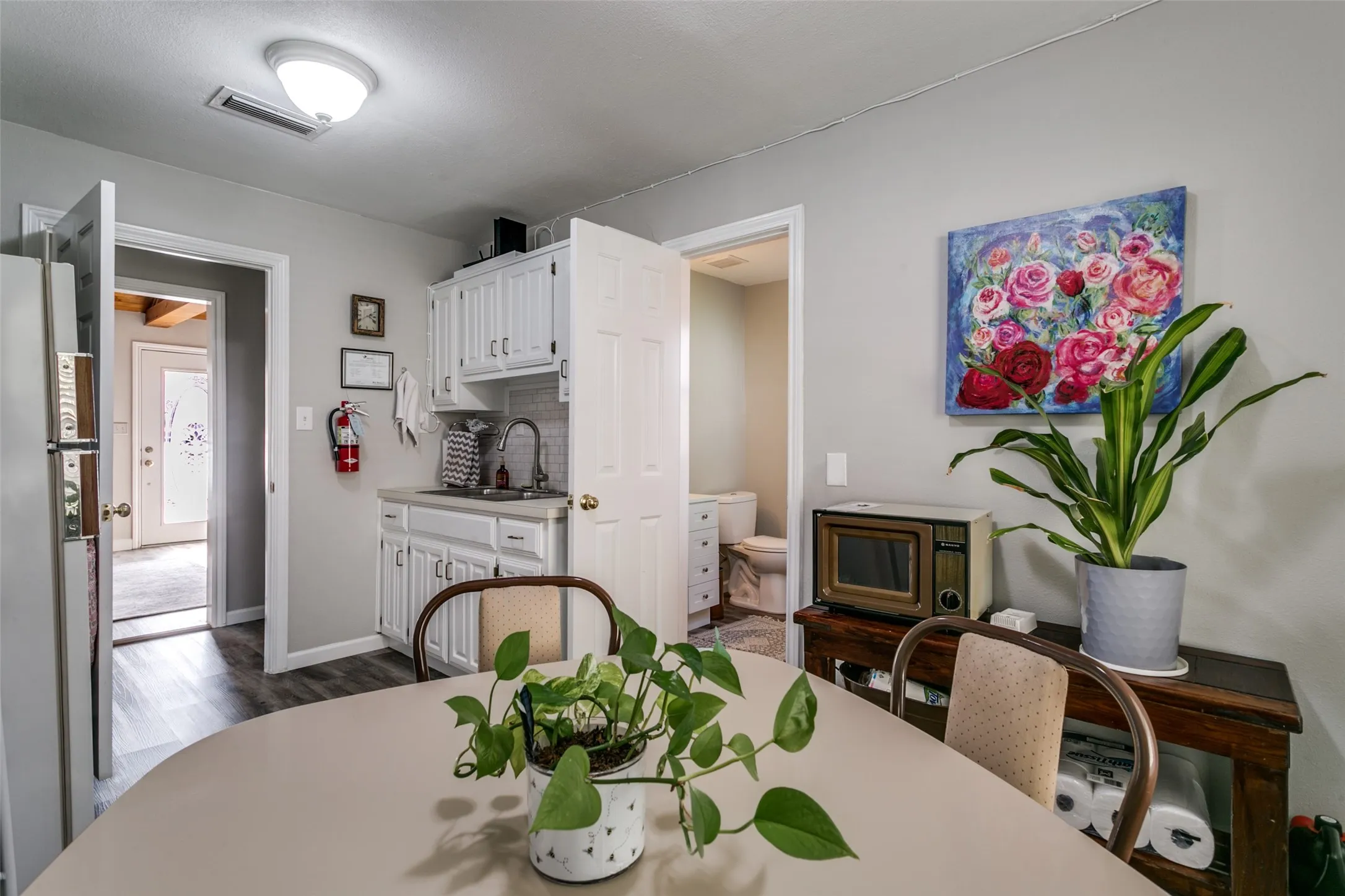 Compact kitchen area featuring white cabinetry, a single basin sink, and a tiled backsplash