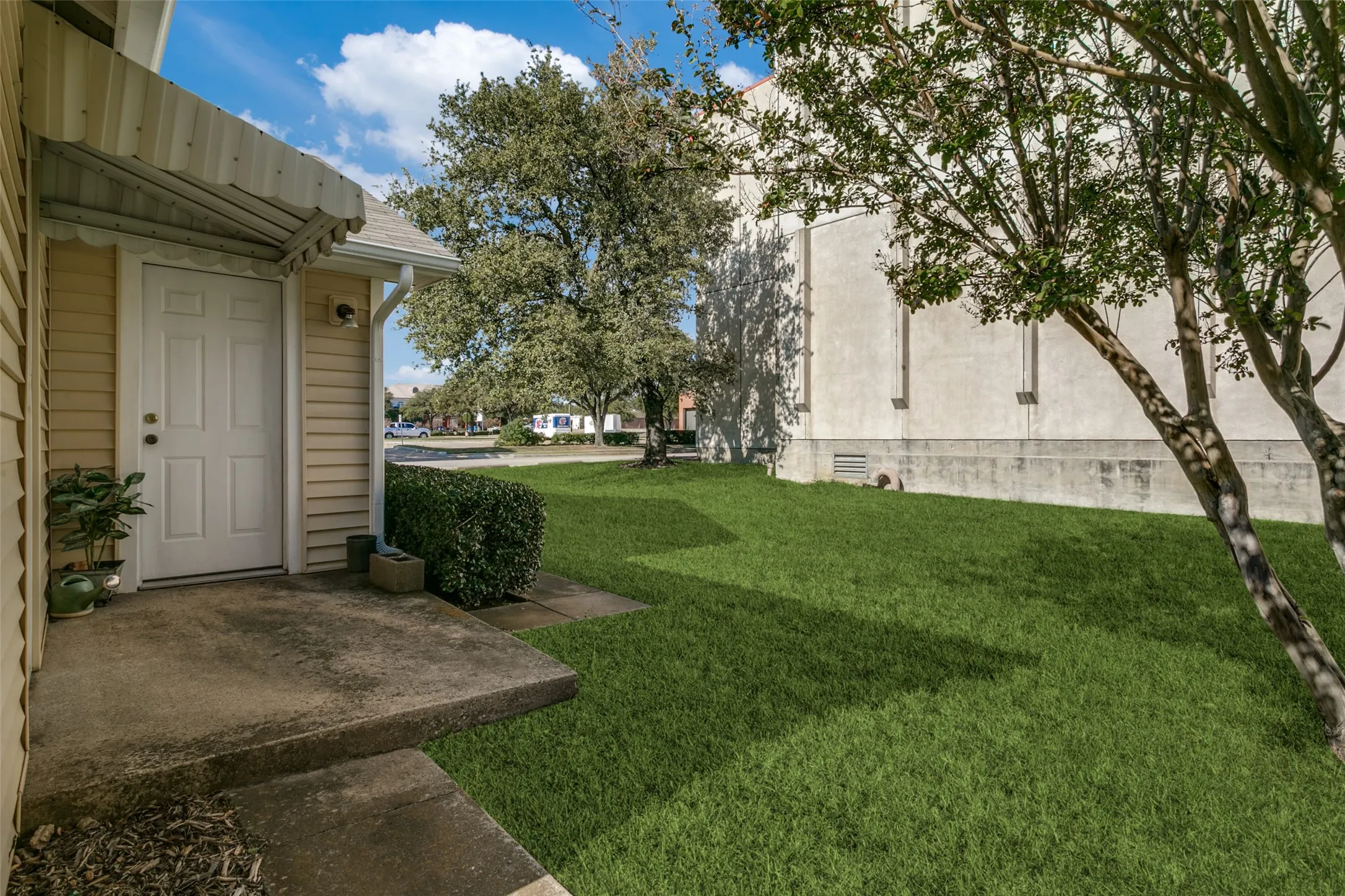 Front entry featuring a concrete porch, white paneled door, and a protective awning
