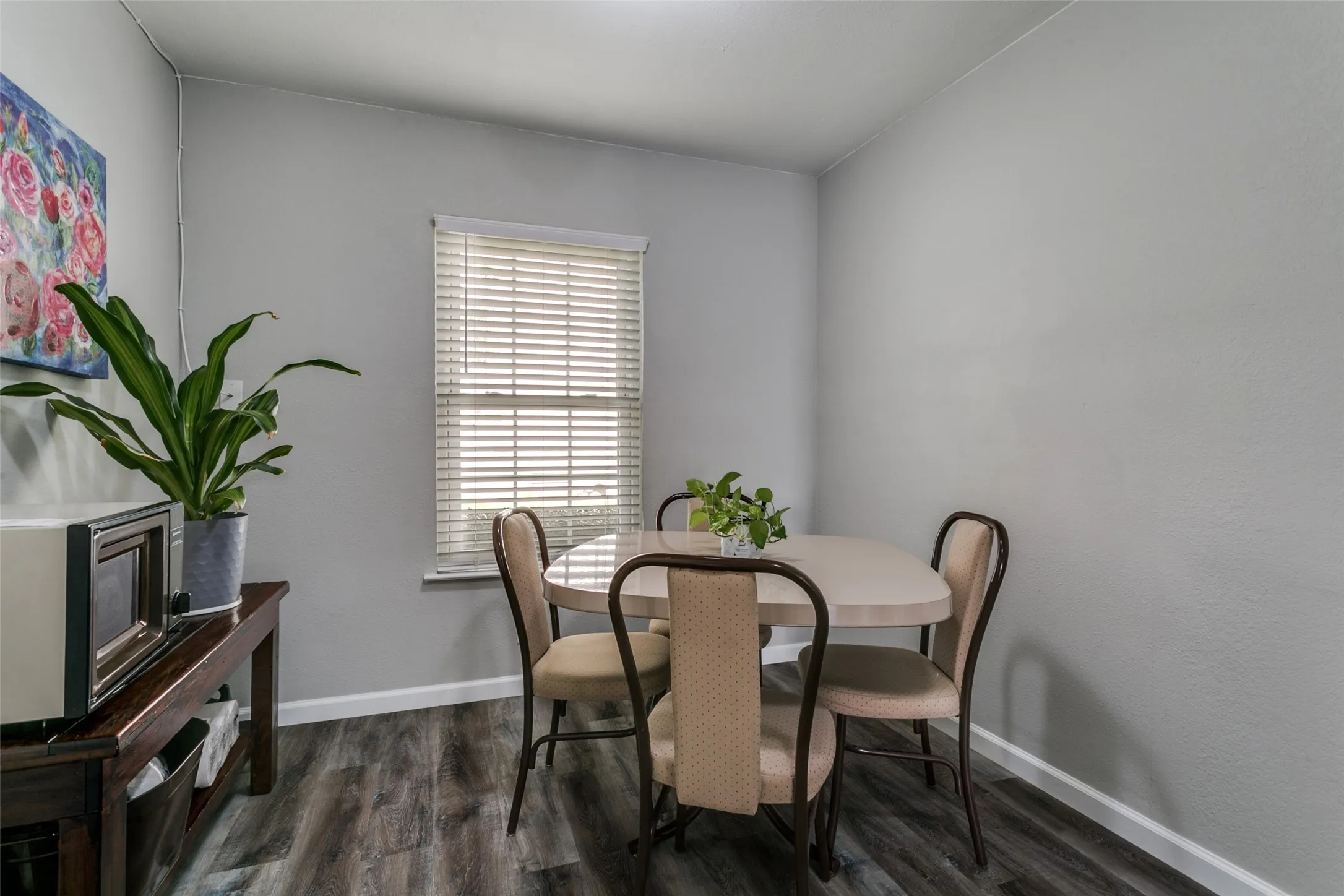 Dining area featuring gray walls, wood-finish flooring, and a window with blinds
