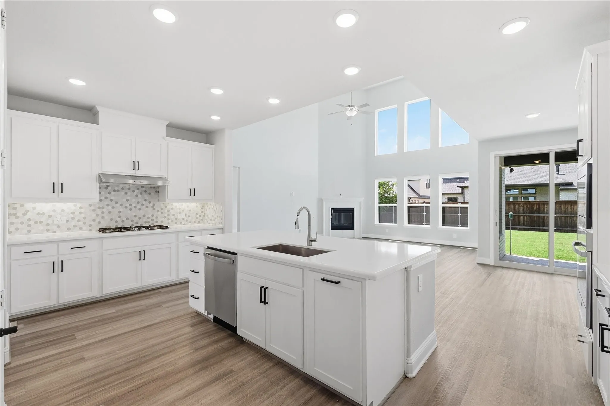 Contemporary kitchen featuring white cabinetry, a large center island with an integrated sink, a stainless steel dishwasher, and wood-finish flooring