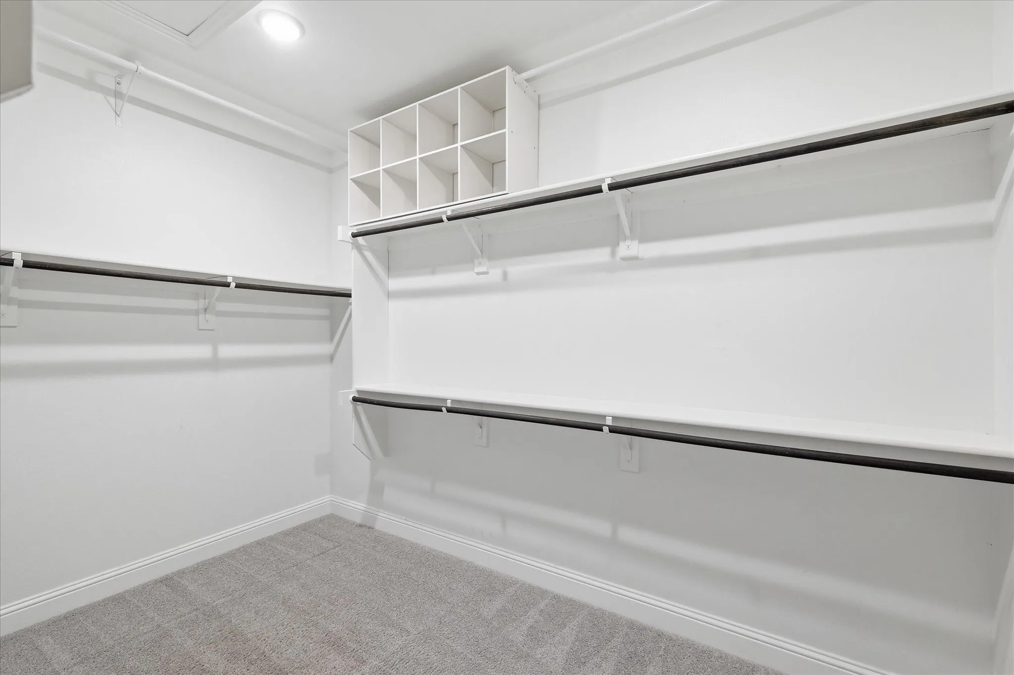 Walk-in closet with integrated shelving, multiple hanging rods, and recessed lighting