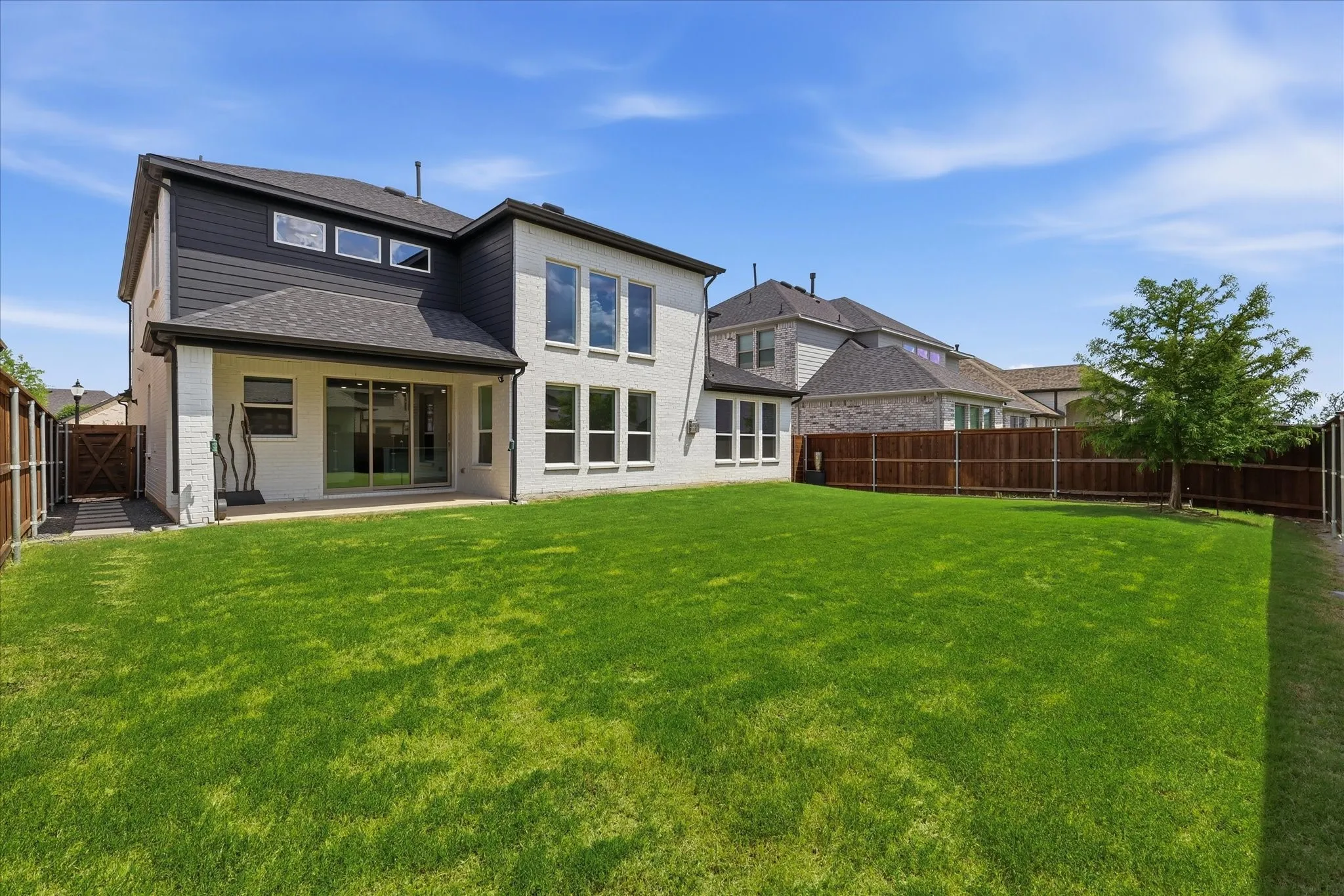 Expansive backyard featuring a manicured lawn, a covered patio, and a privacy fence