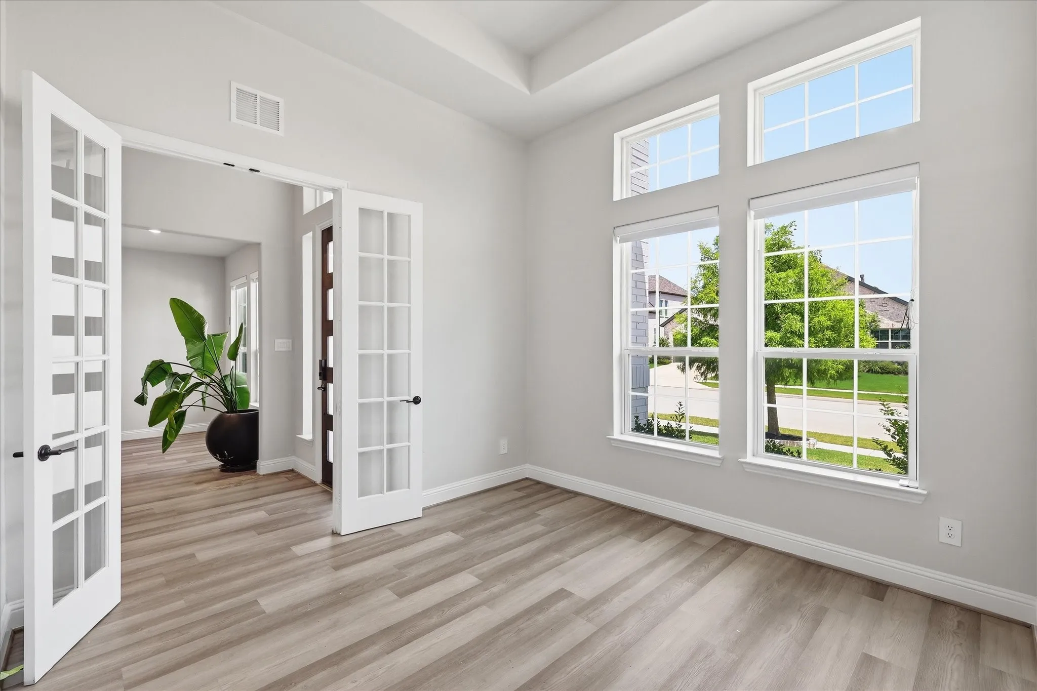 Room featuring French doors, wood-finish flooring, and a tray ceiling