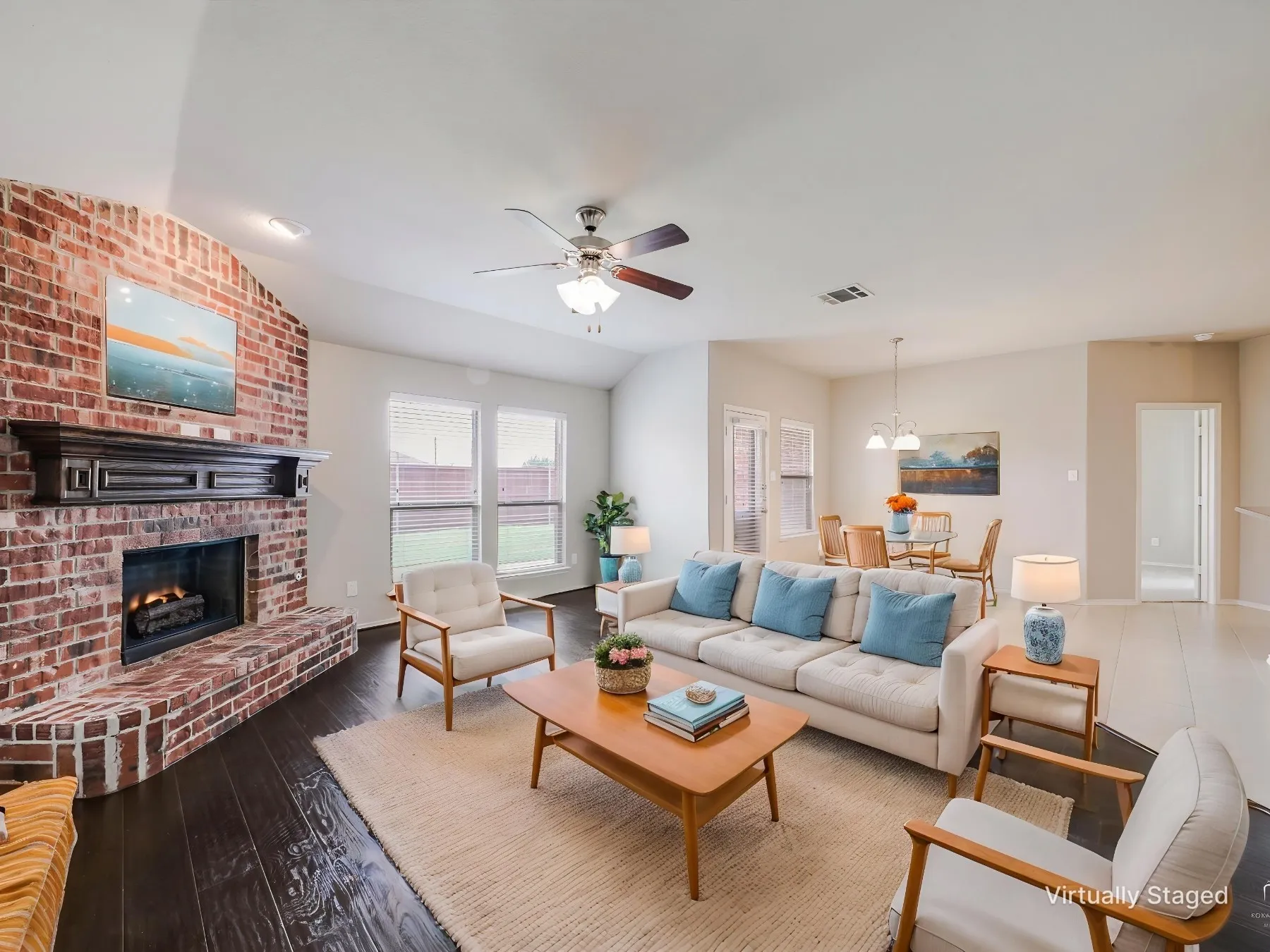 Virtually staged - Spacious living area featuring a brick fireplace with a dark wood mantel, high vaulted ceilings, and dark wood-finish flooring