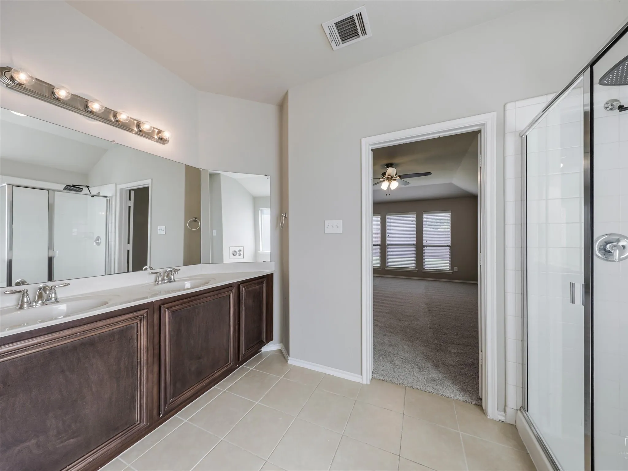 Bathroom featuring a double vanity with dark wood-finish cabinetry and a light-toned countertop, set against neutral wall paint
