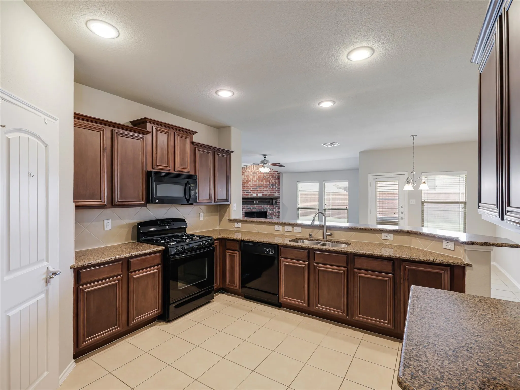 Kitchen featuring wood-finish cabinetry, black appliances, granite-look countertops, and tile flooring
