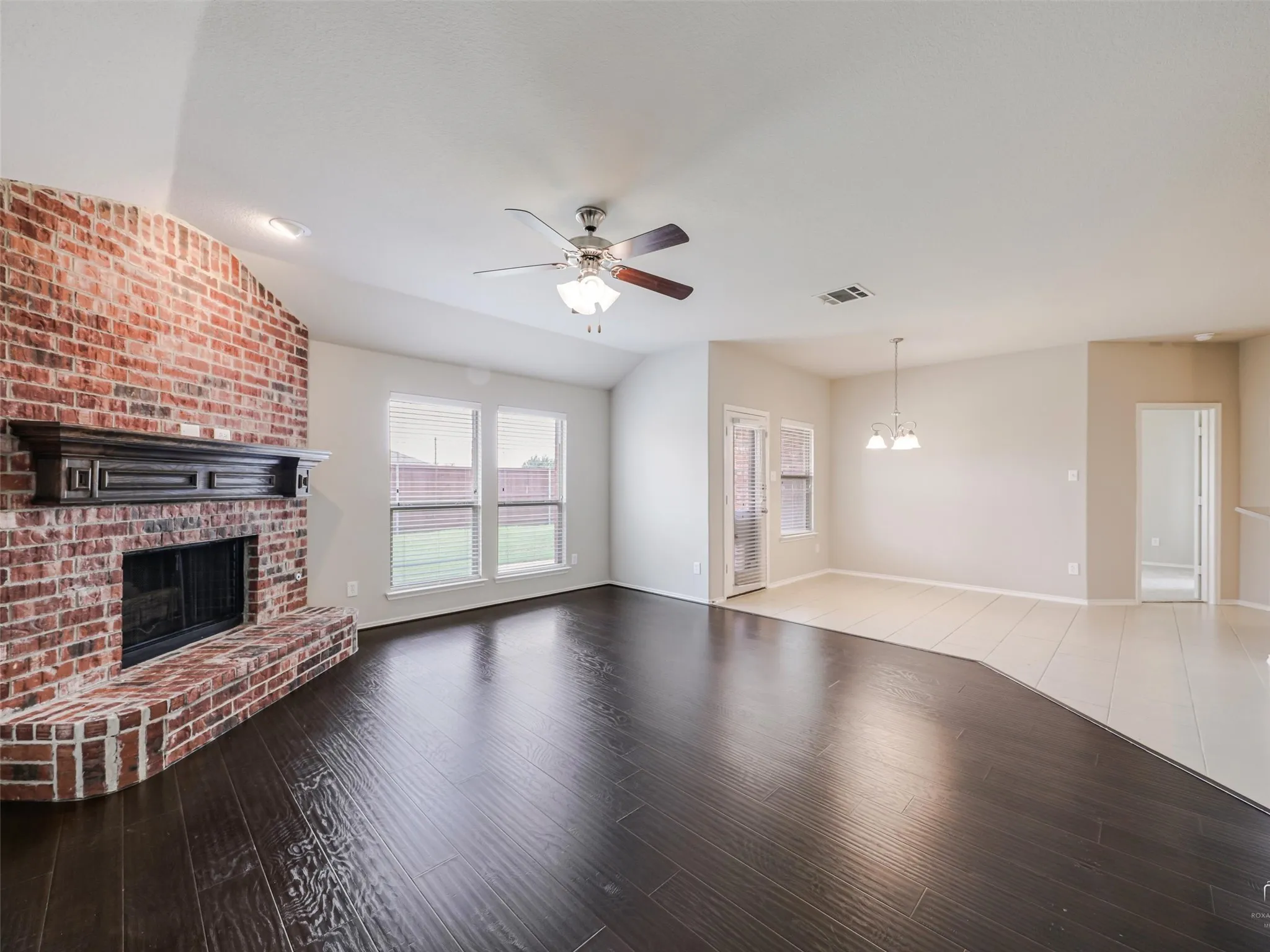 Living area featuring a brick fireplace with a dark wood mantel, dark wood-finish flooring, and a ceiling fan