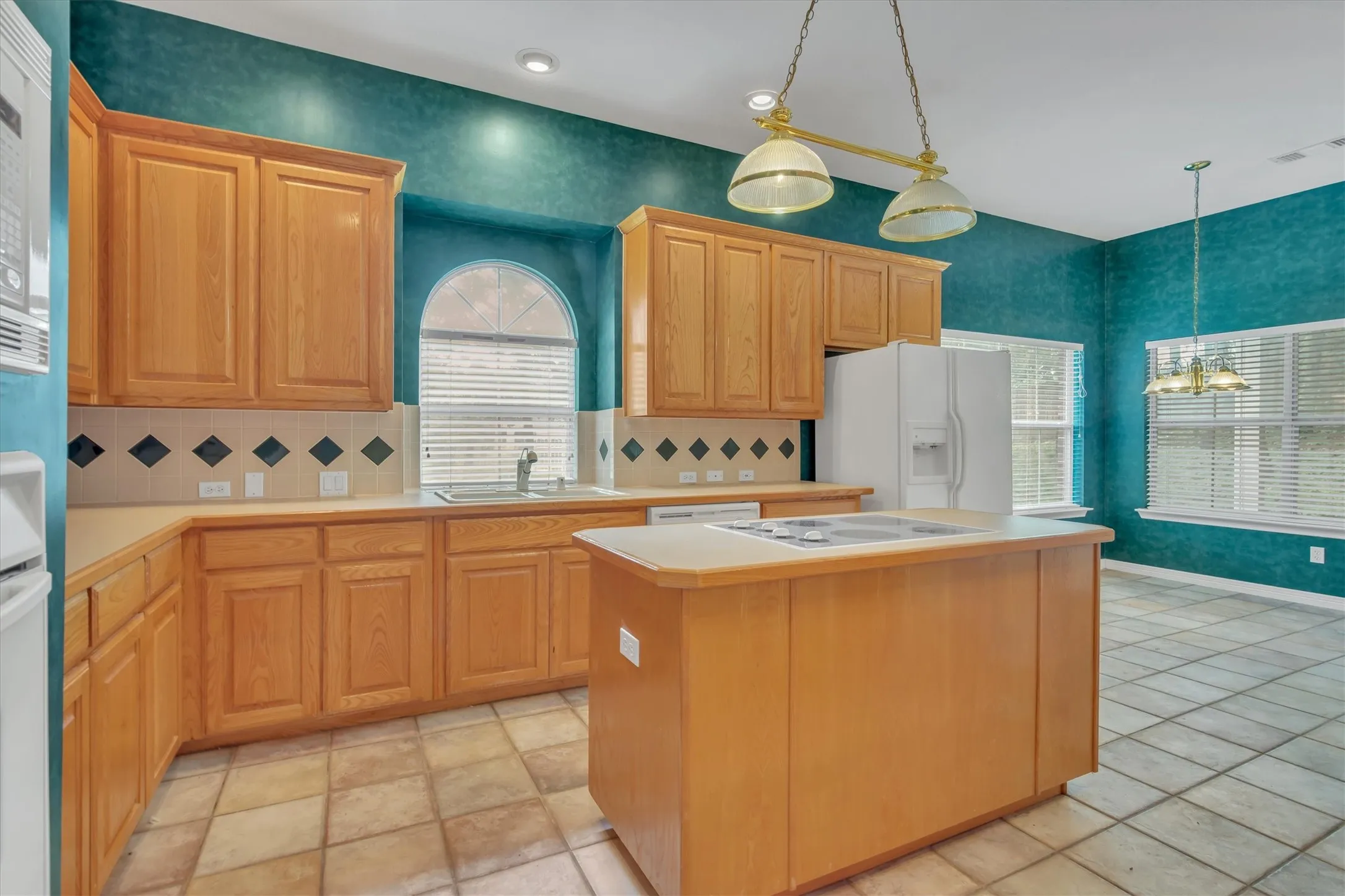Kitchen featuring wood cabinetry, a center island with a built-in cooktop, and neutral tile flooring