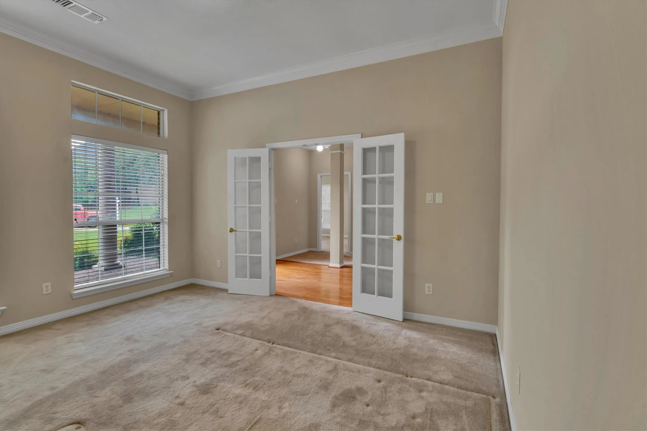Office room featuring double French doors with glass panes, crown molding, and a transom window