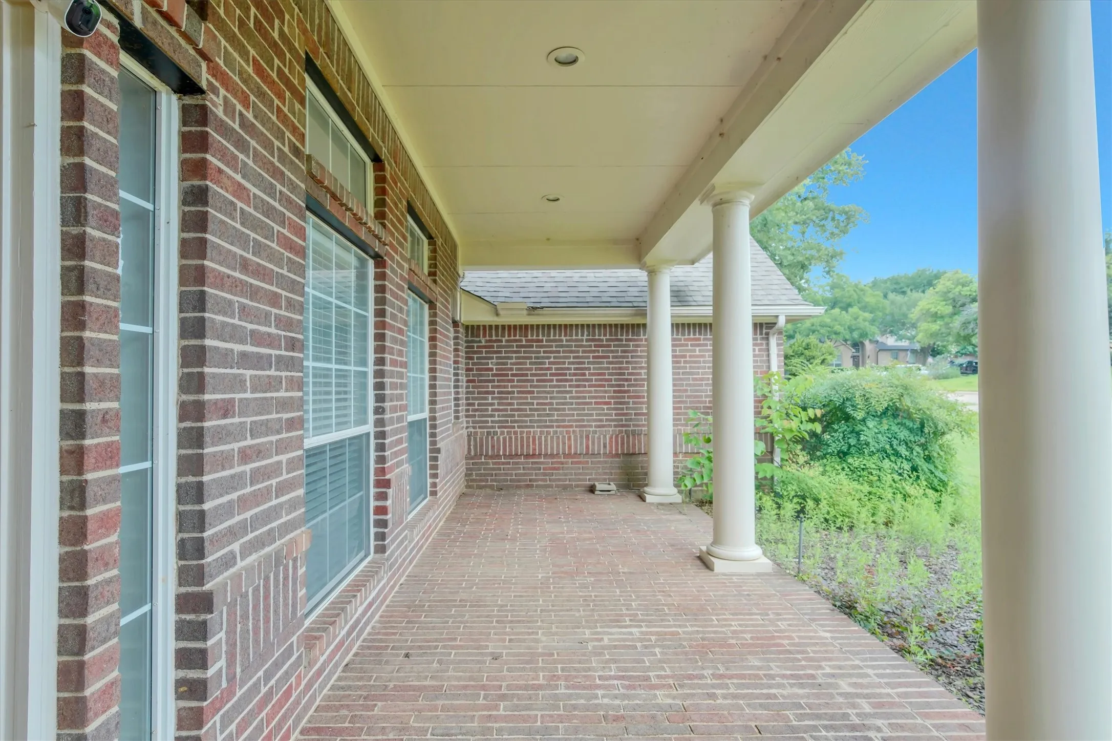 front yard Covered front porch featuring a brick-patterned paver surface